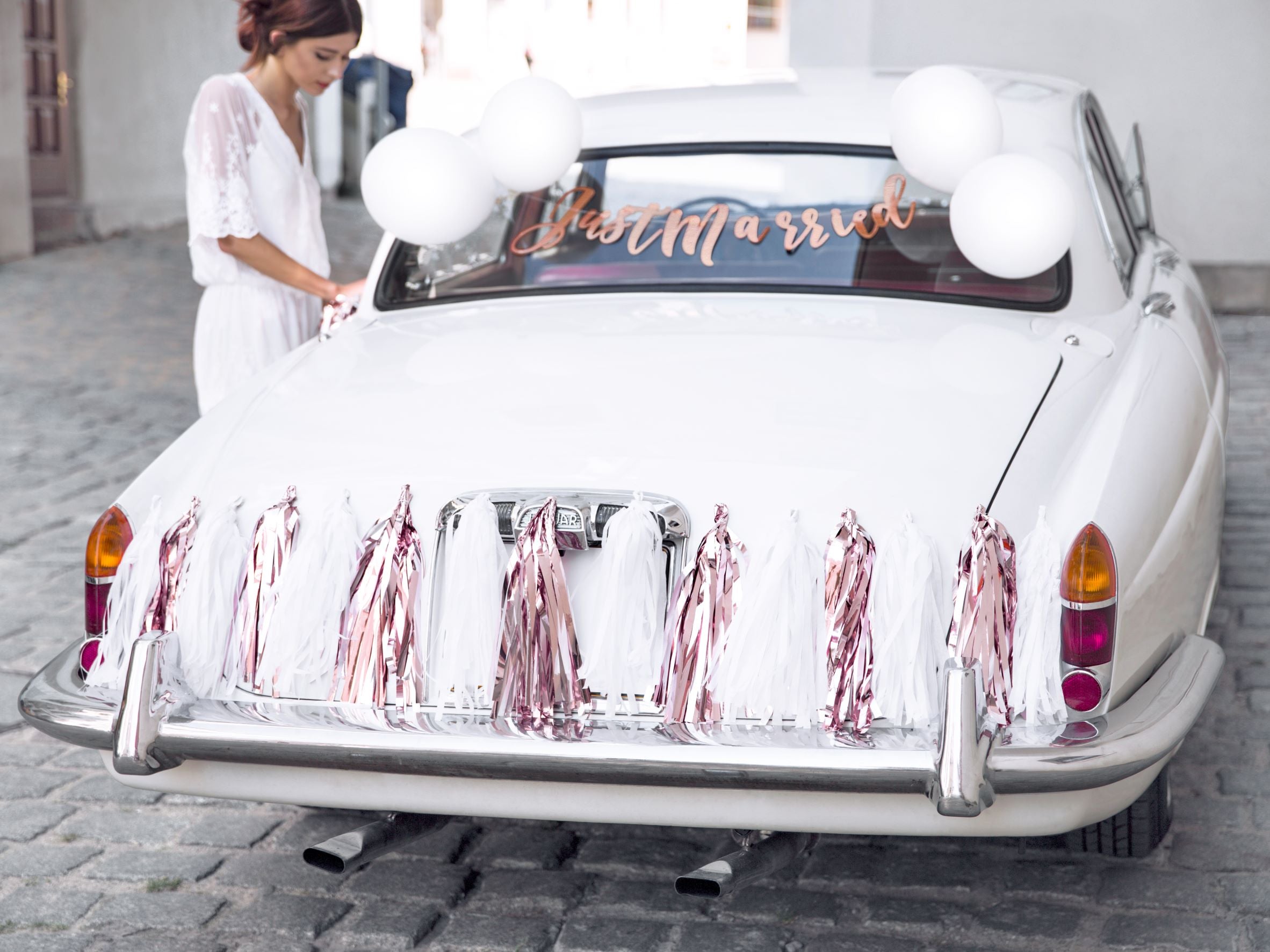 Bride getting into a car decorated with Just Married Wedding Car Kit.