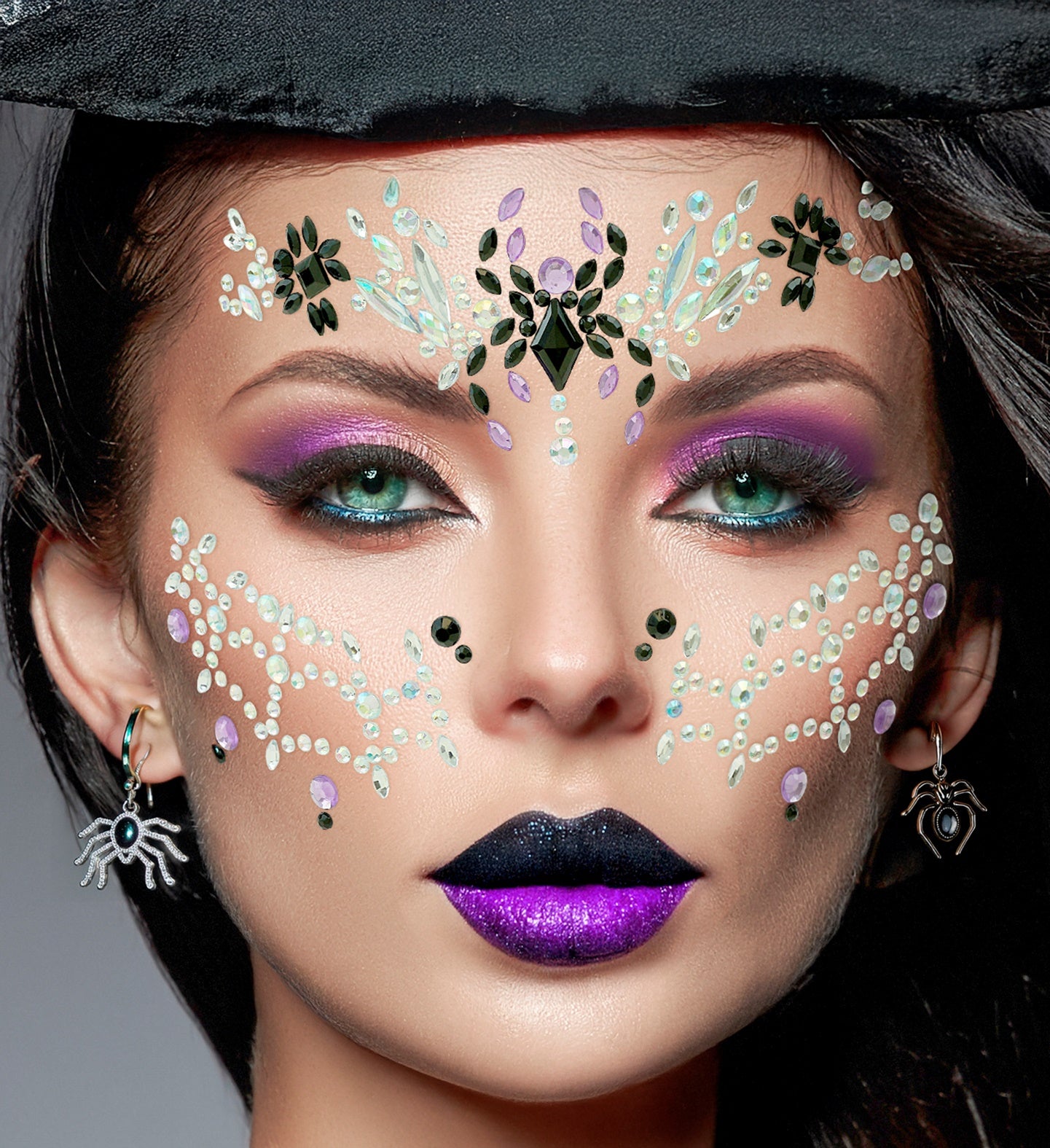 A person wearing dramatic purple makeup, spider earrings, and intricate black widow spiderweb face jewels.