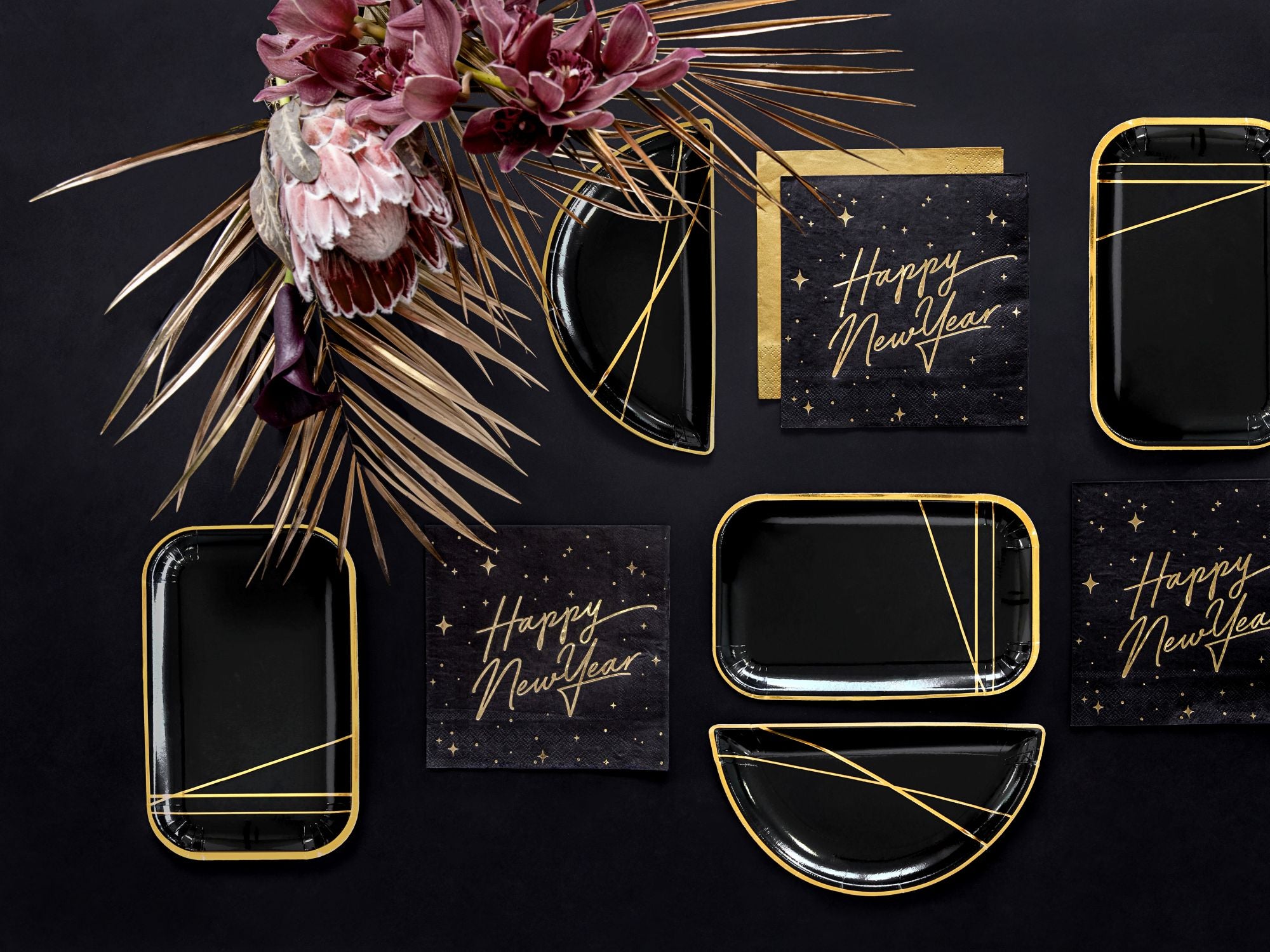 Modern New Year's party tablescape featuring black gold napkins and dried floral decor.
