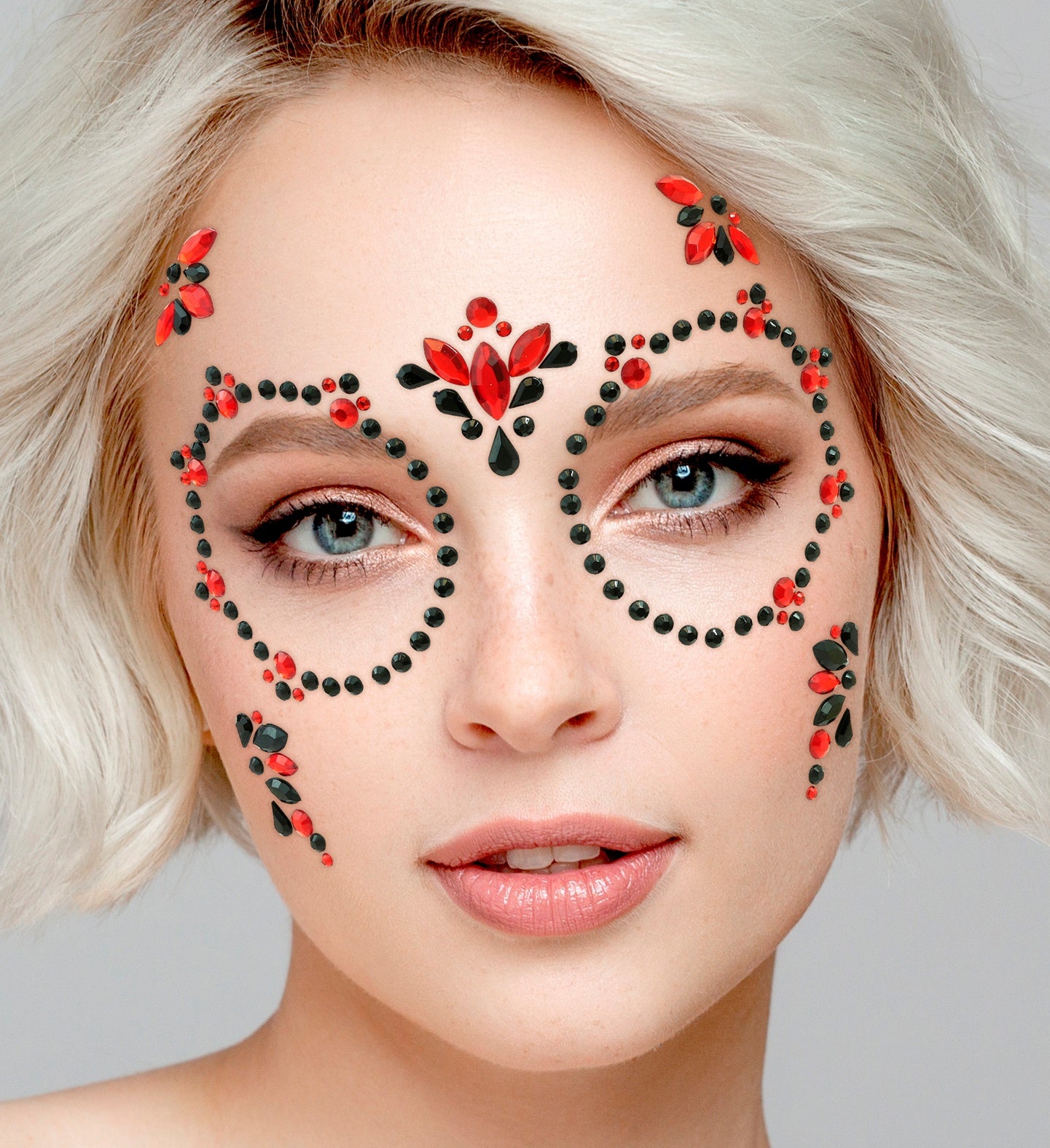 Close-up of symmetrical red and black gem forehead jewels and matching eye frames for a Dia de los Muertos costume.