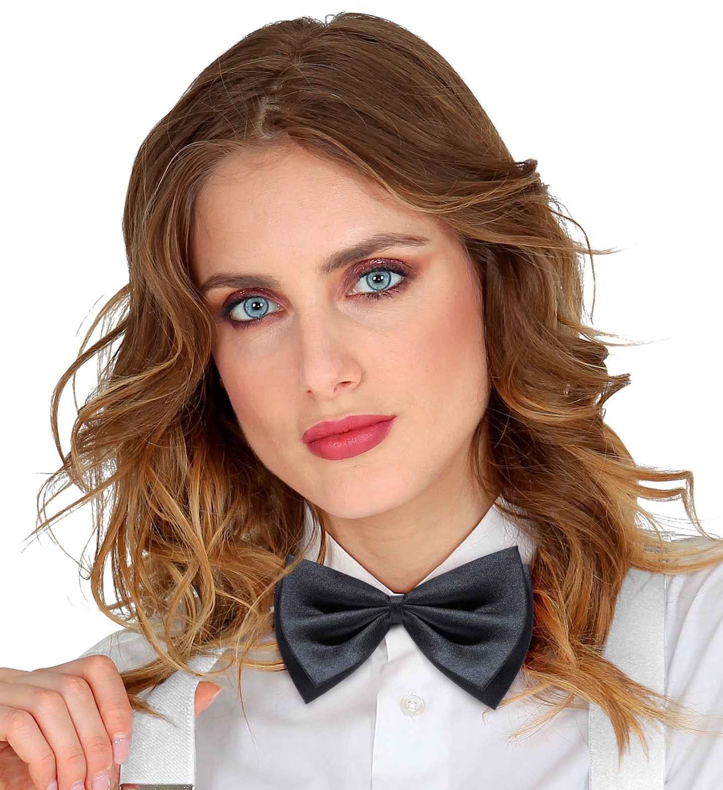 A close-up of a woman with long wavy hair, wearing a black satin bowtie and a white shirt with white suspenders.