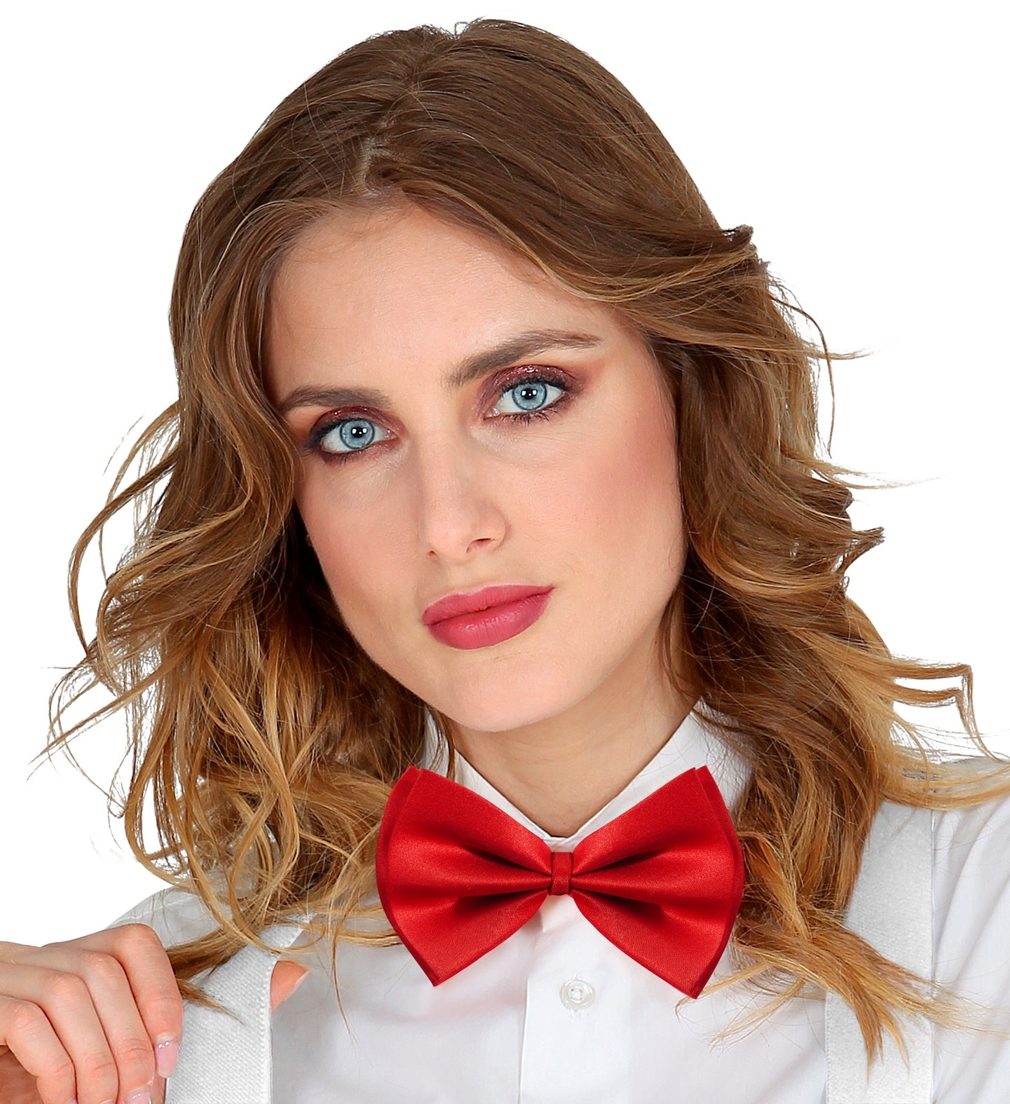 A close-up of a woman with long wavy hair, wearing a red satin bowtie and a white shirt with white suspenders.
