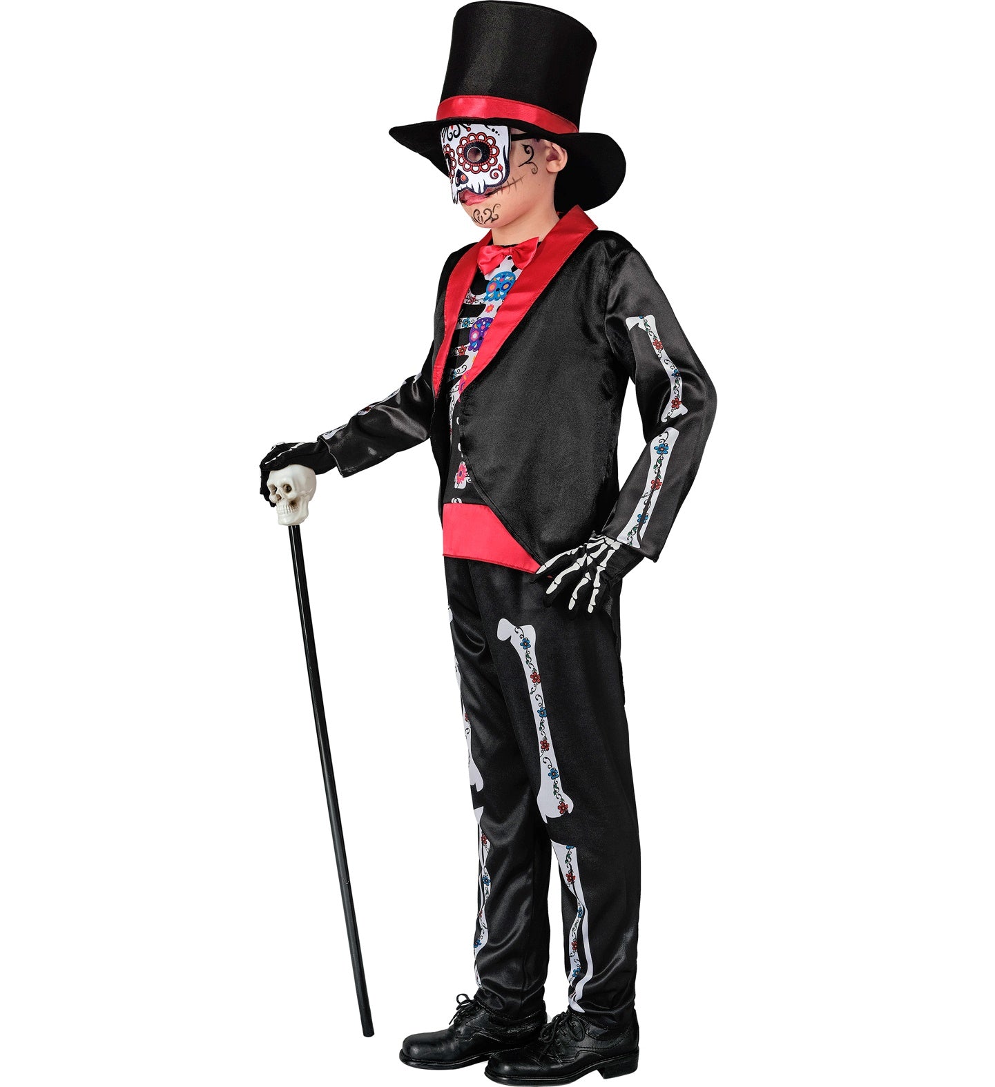 A side profile of a child in a Dia De Los Muertos costume, holding a cane. The costume includes a black tailcoat, pants with a skeleton print, a top hat, and a mask with sugar skull face paint.
