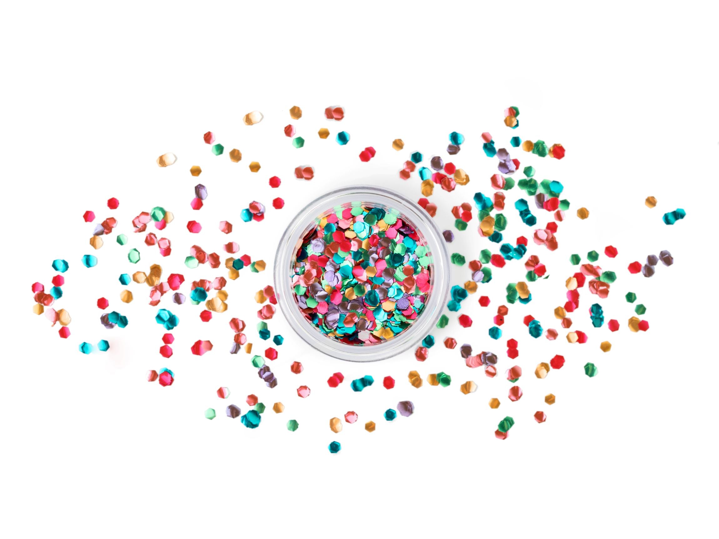 A clear jar filled with a mix of colourful, hexagonal glitter pieces, with some scattered around the jar, against a white background.