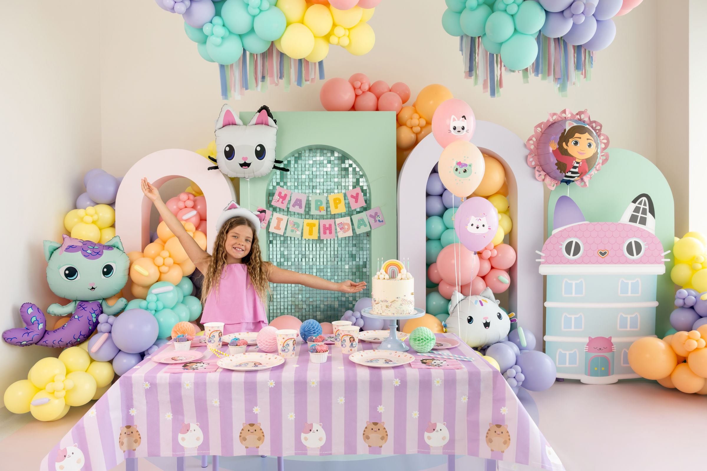 Child at a Gabby's Dollhouse themed birthday party with colorful decorations and balloons