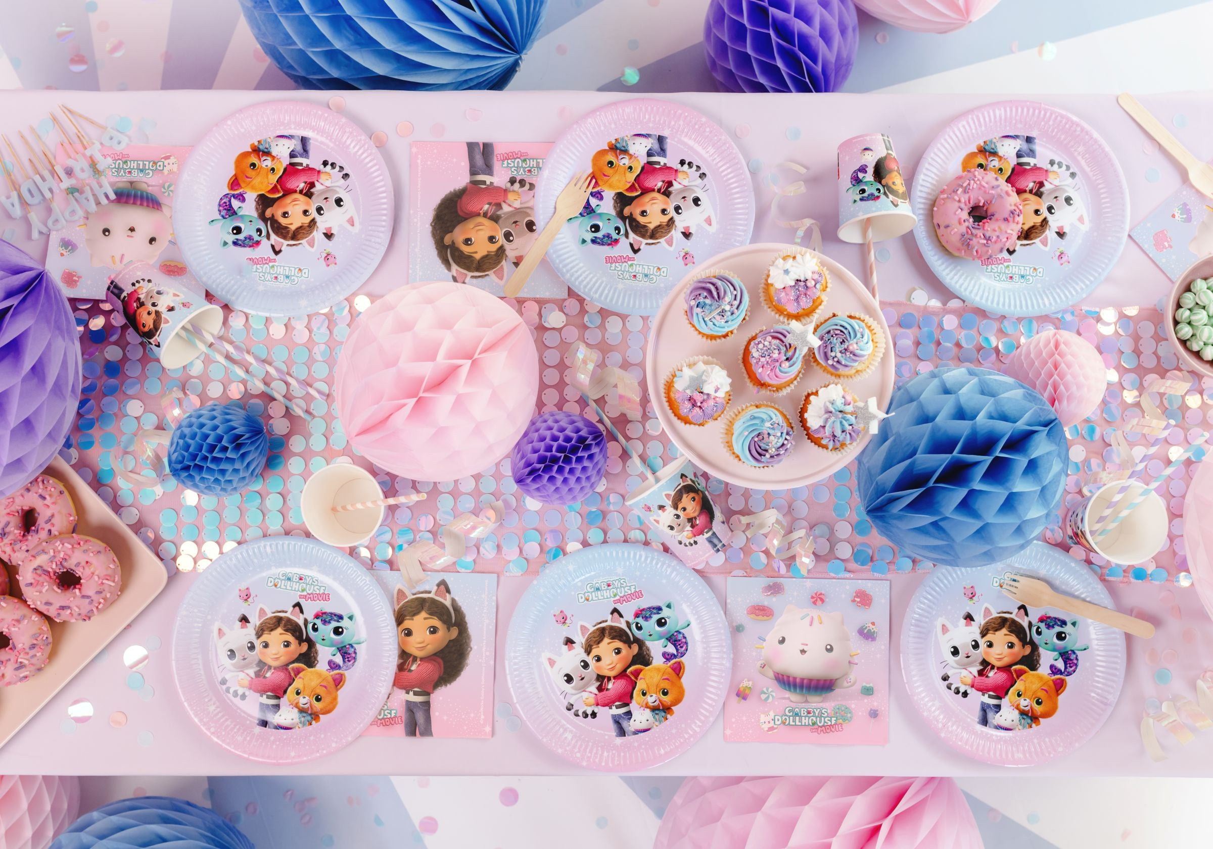 A beautifully decorated party scene with Gabby's Dollhouse movie napkins, plates, and balloons.