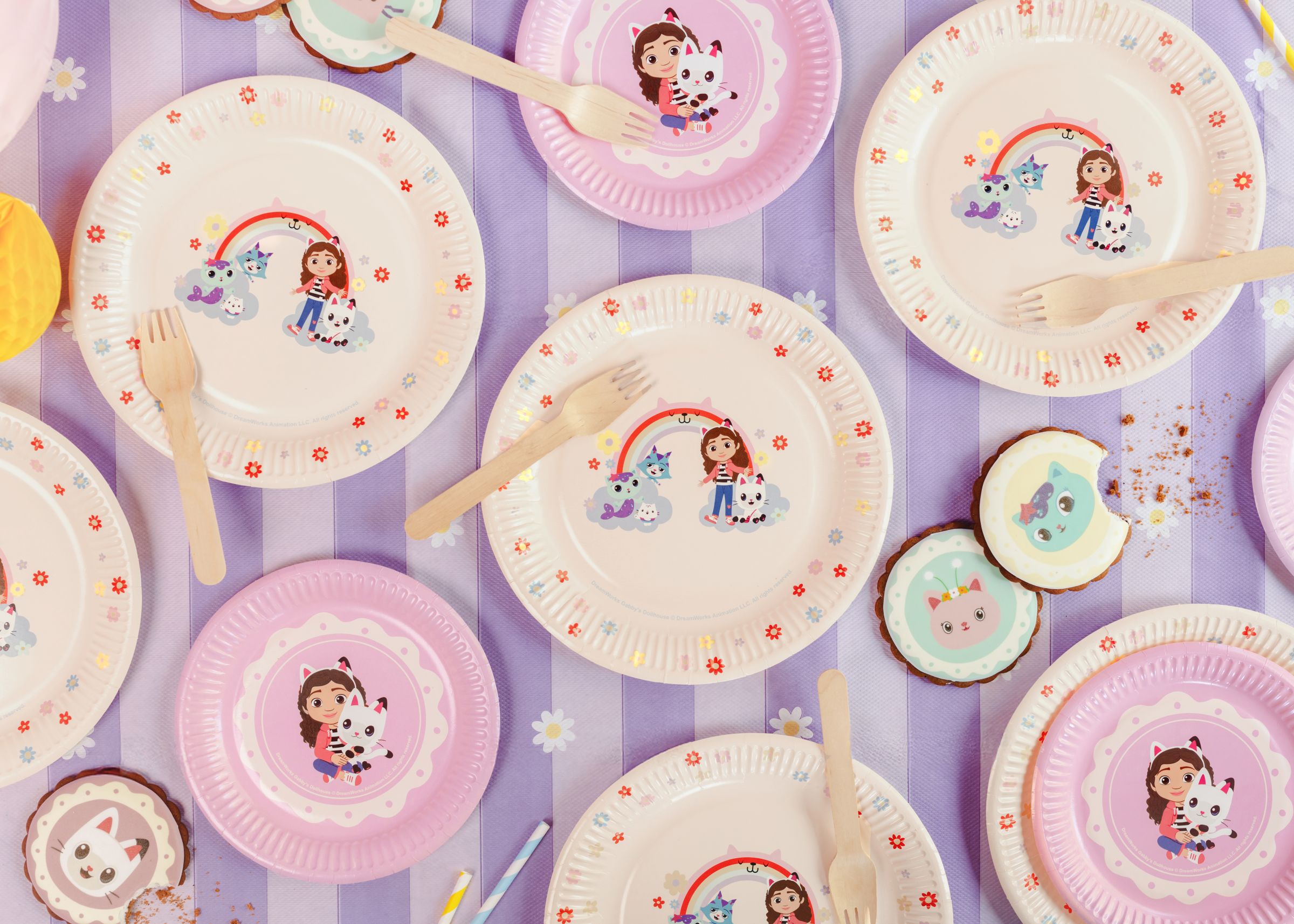 Colorful paper plates with Gabby's Dollhouse characters on a purple striped background