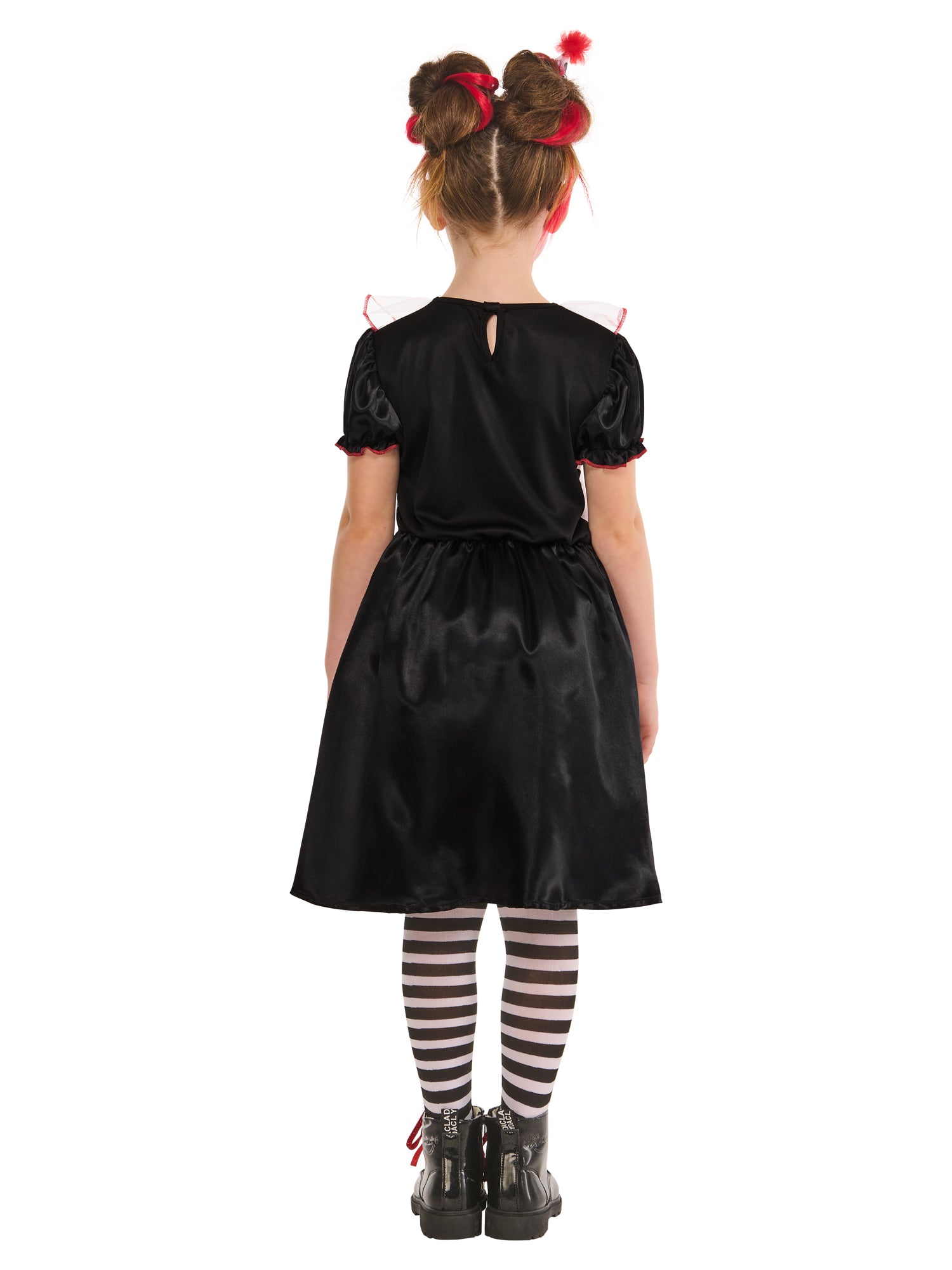 A back view of a child in a black and white clown costume. The costume consists of a black and white dress, a ruffled collar, and black and white striped leggings. The child is wearing a headband with a small hat and her hair is in two buns with red accents.