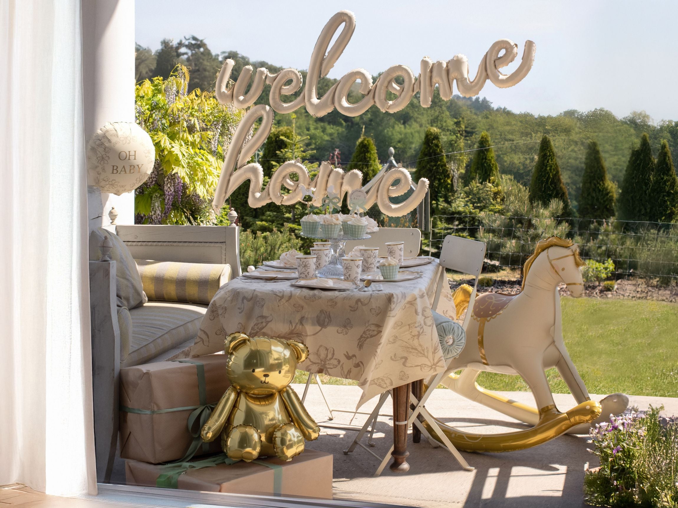 A cream rocking horse balloon used as table decor for an outdoor Welcome Home baby shower.