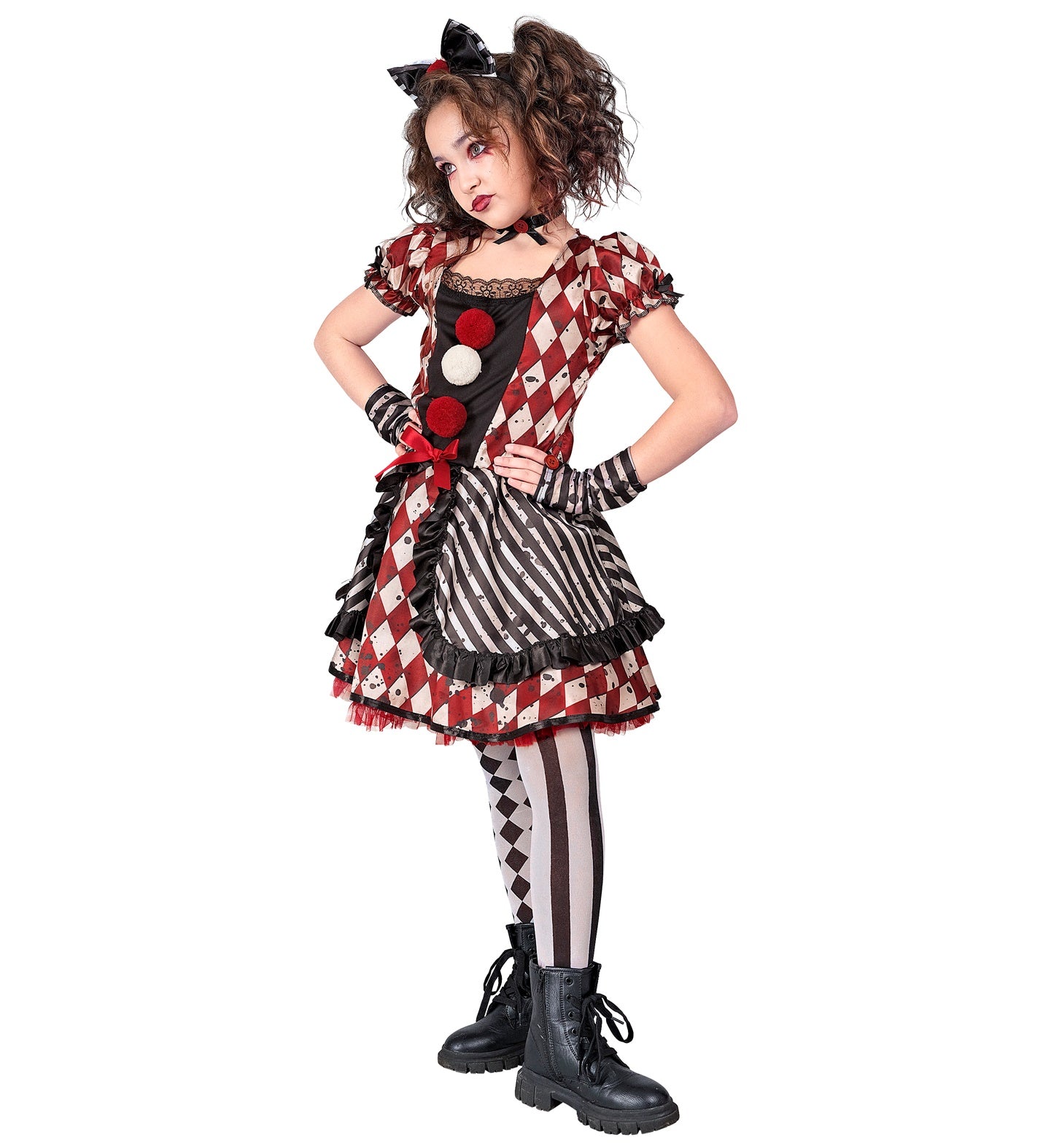 A child from the side profile, posing in a Harlequin Doll Clown costume, featuring a black and red bow headband, a black choker, a red and white diamond-patterned and black and white striped dress with ruffles and pom-poms, black and white patterned tights, and matching striped glovelettes. The child has dramatic eye makeup and red lipstick.