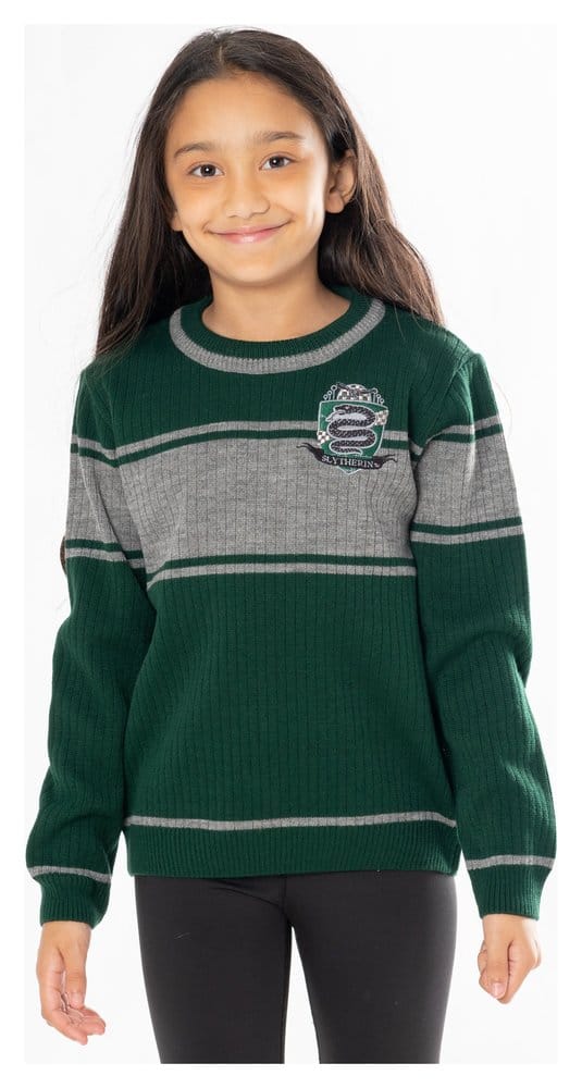 A smiling child modeling an officially licensed kids' Harry Potter Slytherin fancy dress jumper, featuring a green ribbed knit with grey stripes and an embroidered snake crest.