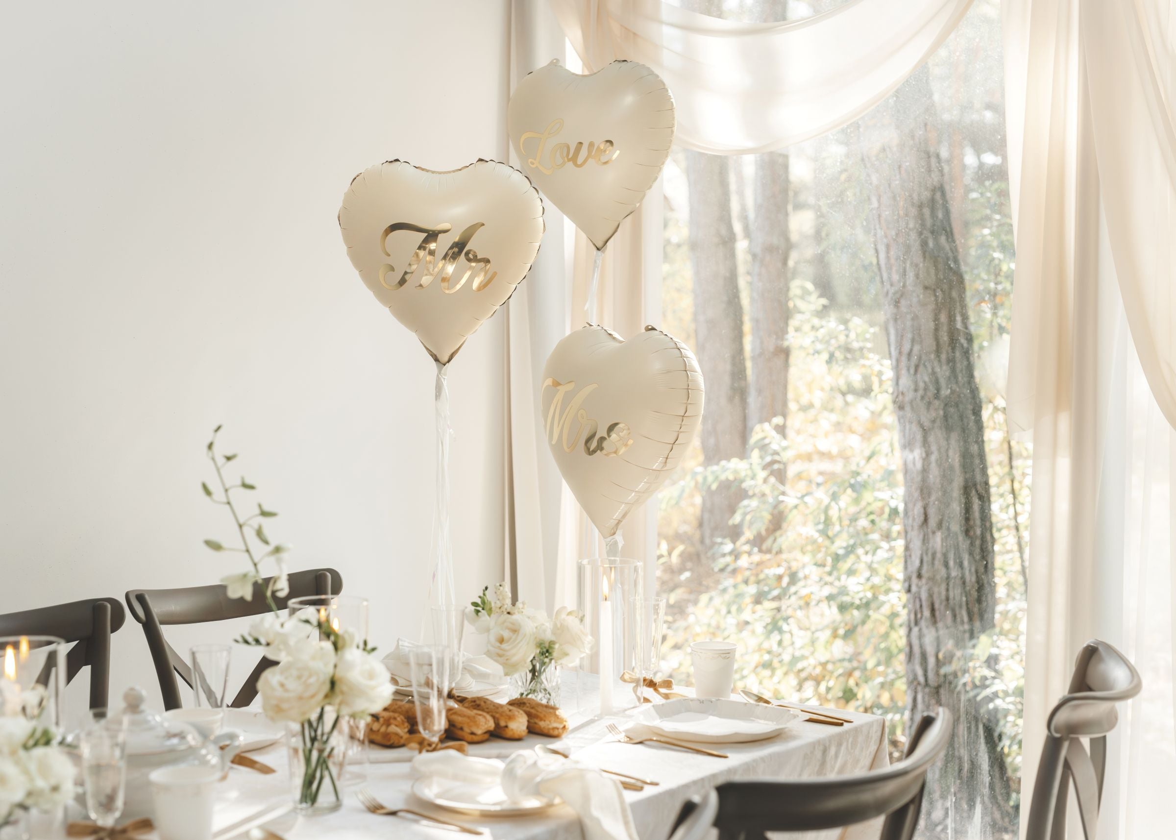 Beige heart balloons with gold Mr and Mrs text used as elegant table centerpieces at a wedding reception.
