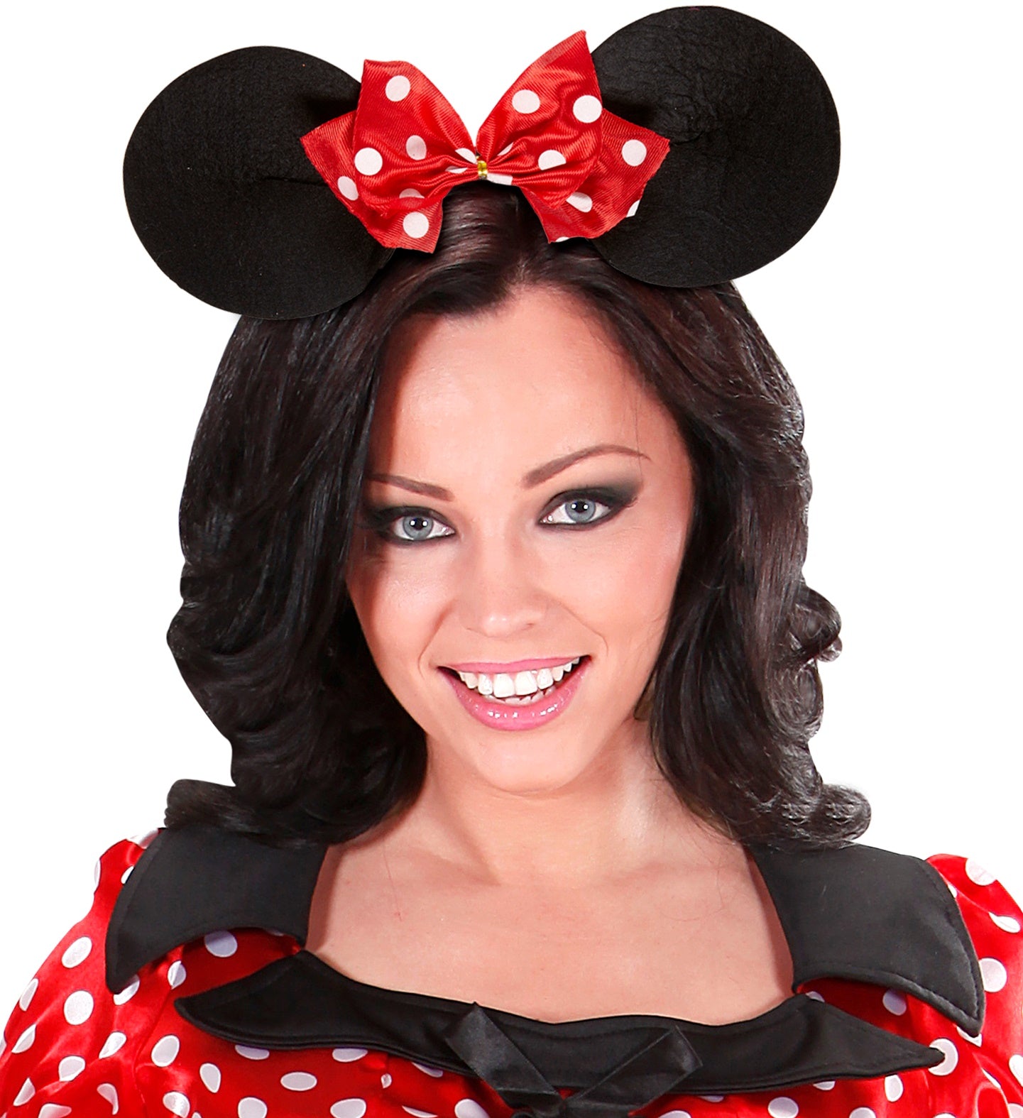 Woman smiling wearing a black mouse ears headband with a red and white polka dot bow, matched with a red dotted dress.