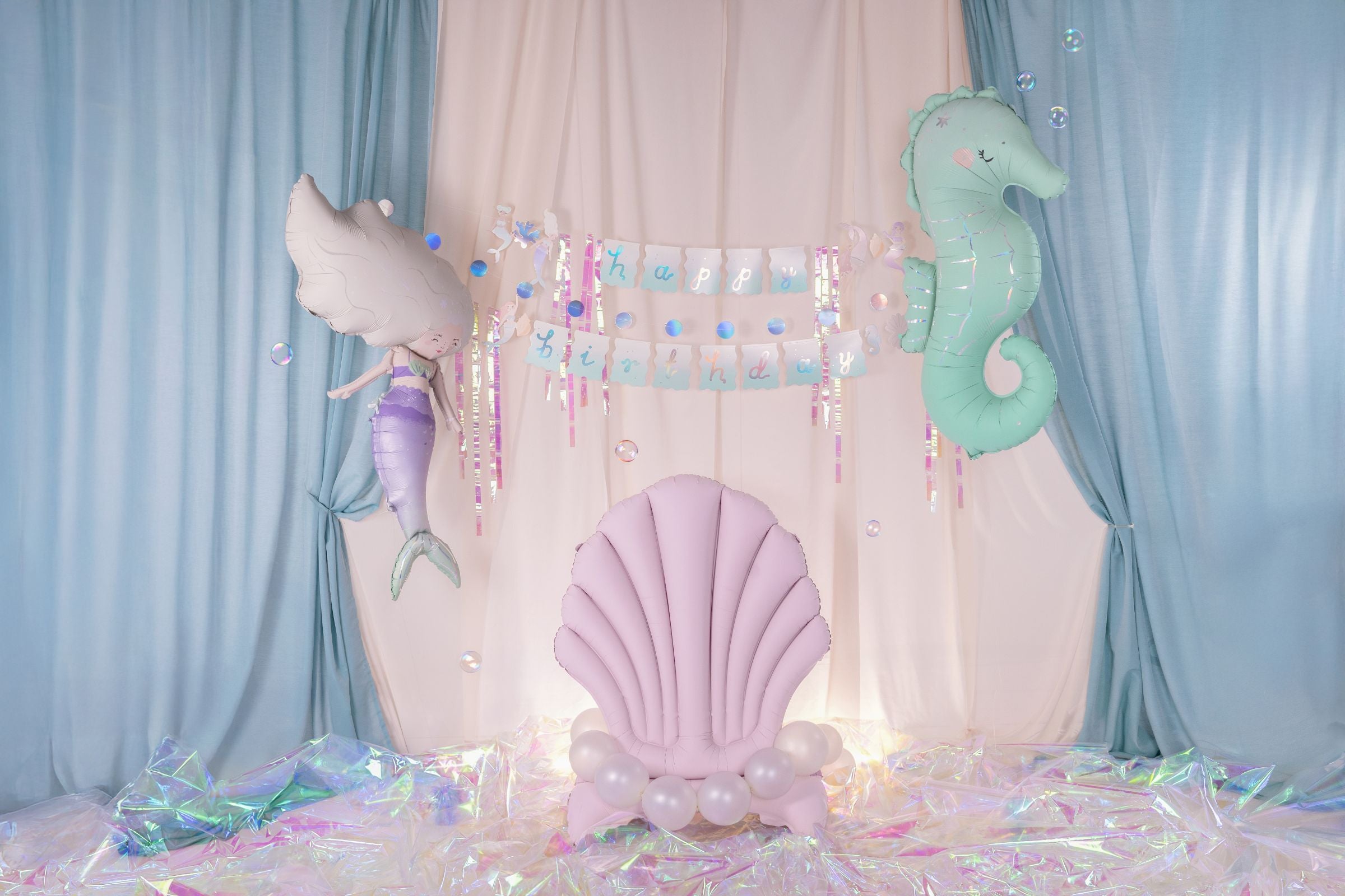 Pastel-colored chair with shell design, mermaid, whale, and seahorse decorations against a light blue curtain backdrop.