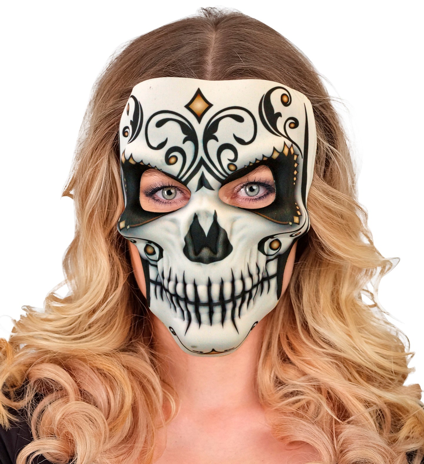 A woman with blonde hair and green eyes models a decorative Day of the Dead sugar skull mask with black and gold scrollwork.