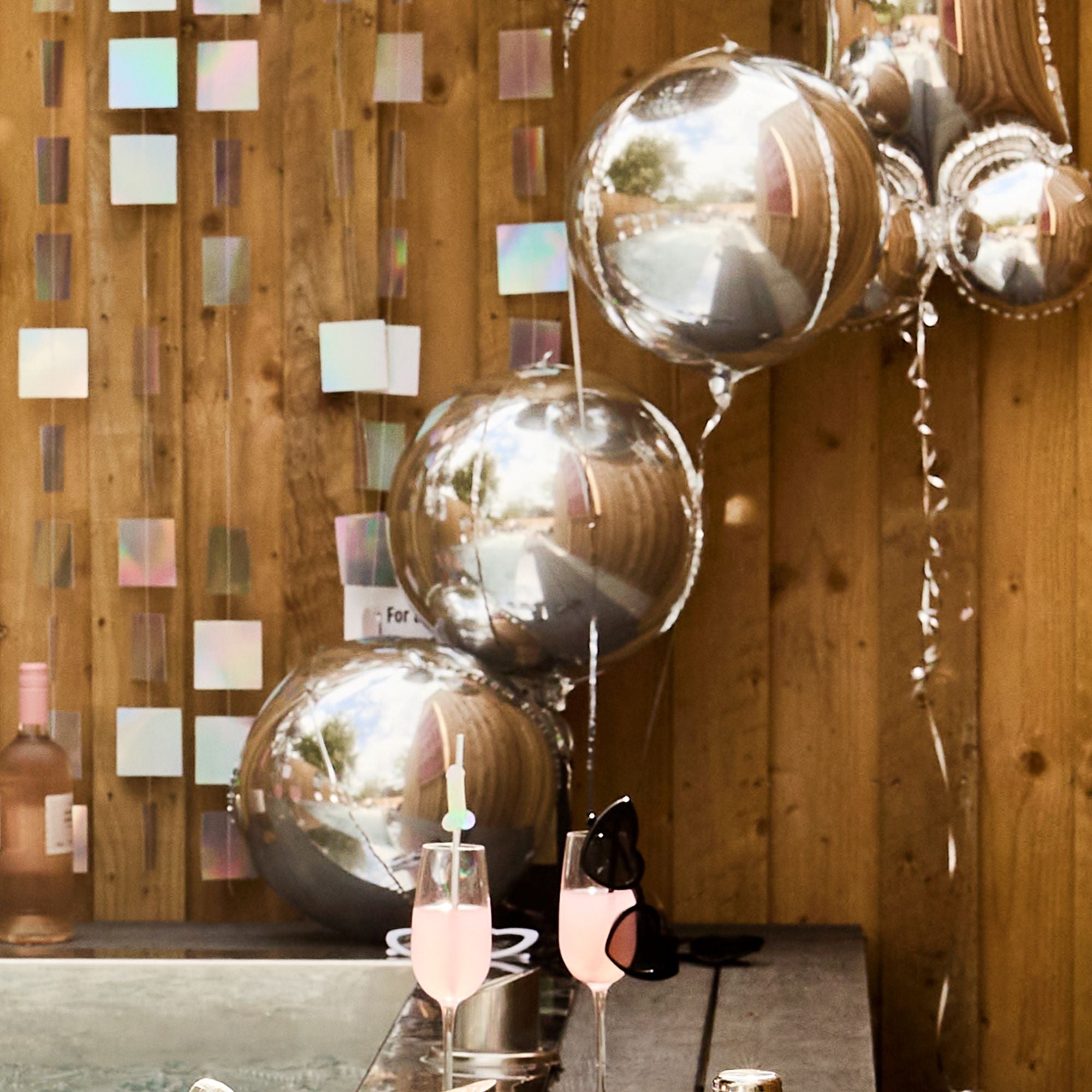 Metallic silver 15-inch spherical balloons used as elegant table decor for an outdoor celebration.