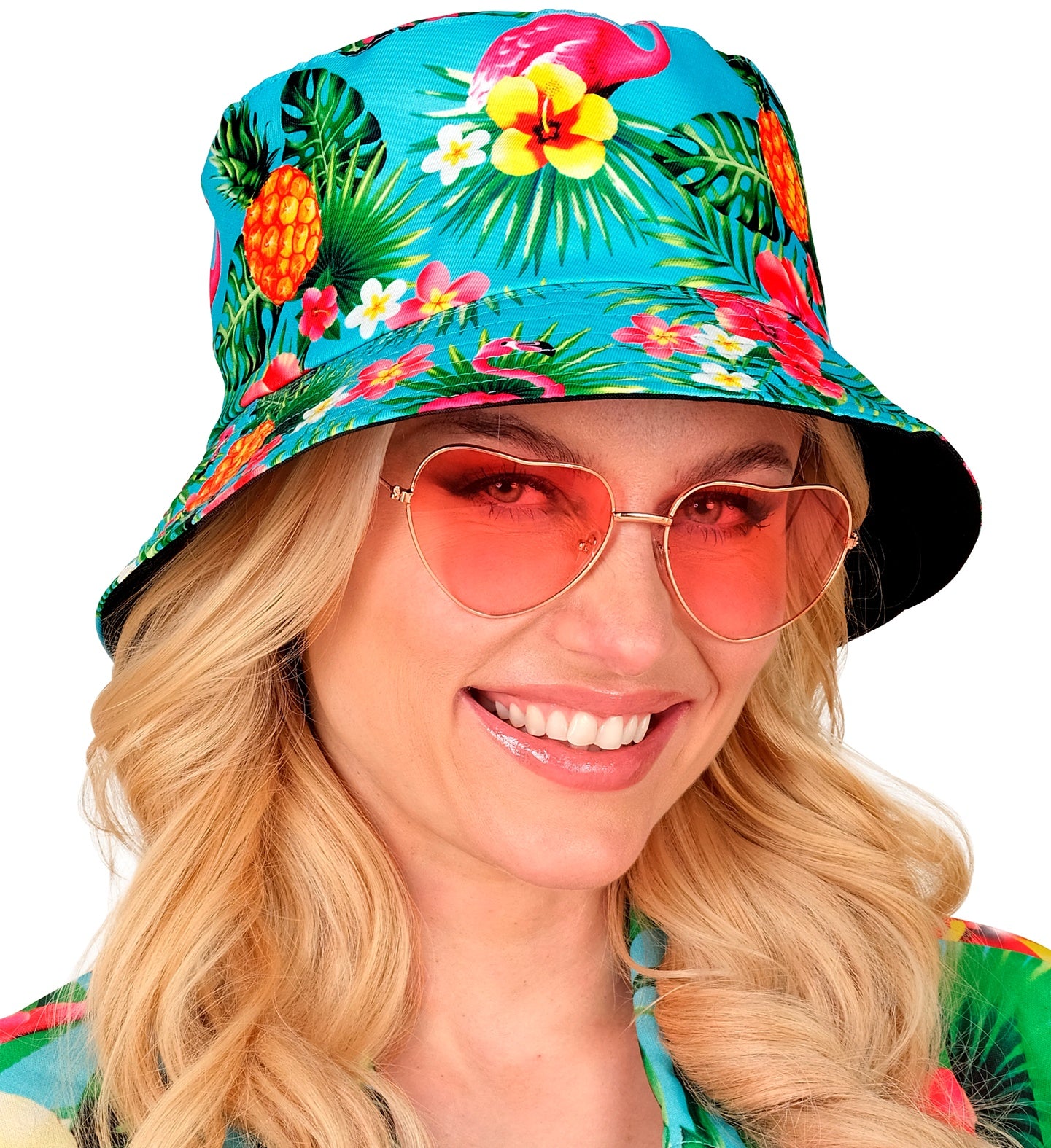 A woman wearing a neon blue tropical bucket hat with flamingo and pineapple prints, styled with pink heart-shaped sunglasses.