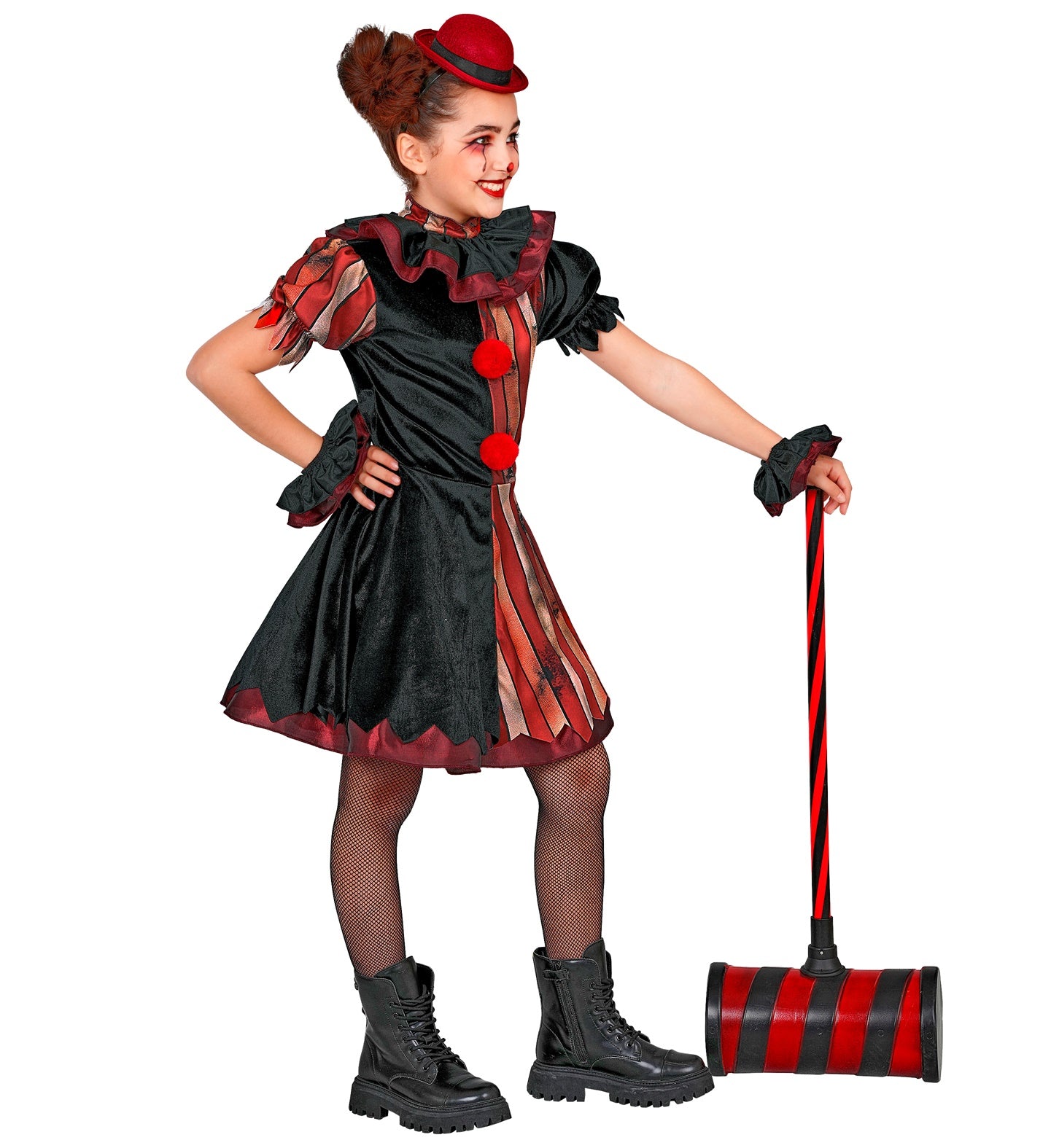 A young girl smiling and leaning on a large toy carnival hammer, wearing a wicked clown fancy dress costume featuring a jagged-hem dress, black fishnet tights, lace-up boots, and ruffled wrist cuffs.