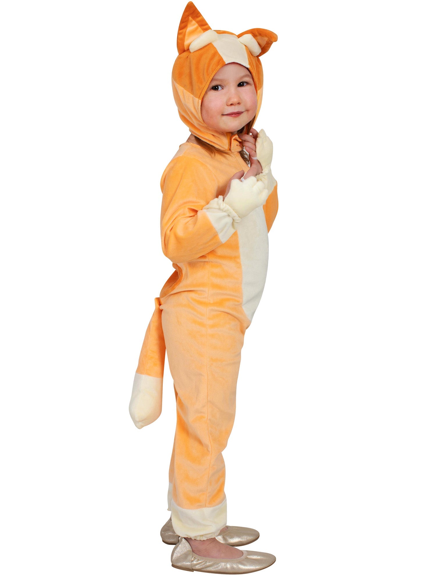 A young child wearing an orange and white Bingo costume, consisting of a full jumpsuit with an attached tail and a detachable headpiece with ears, posing with hands near their face and smiling playfully.