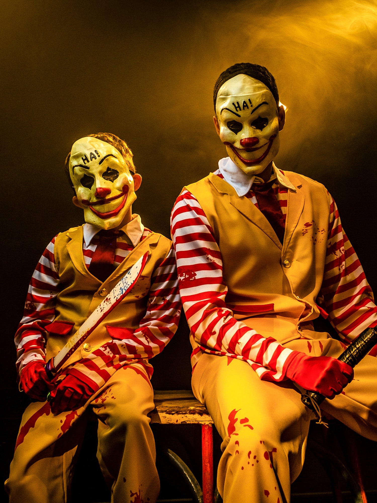 Scary clown costumes for kids and adults with striped shirts, yellow trousers and sinister clown masks