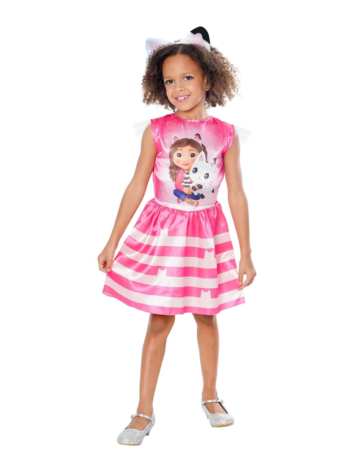 A smiling young girl modelling a bright pink Gabby's Dollhouse fancy dress costume, featuring a printed bodice of Gabby and Pandy Paws, sheer flutter sleeves, a pink and white striped skirt with cat silhouettes, and a matching cat-ear headband.