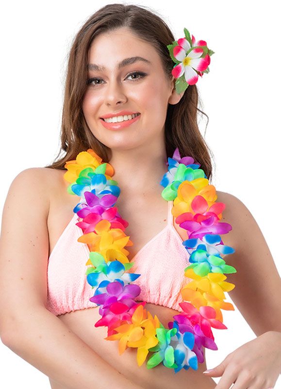 A smiling model wearing a vibrant, chunky rainbow-coloured two-tone Hawaiian orchid lei garland over a light pink bikini top, styled with a matching tropical flower clip in her hair.
