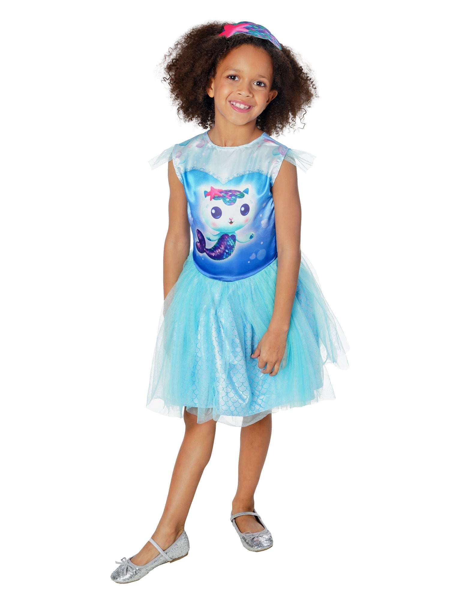 A smiling young girl modelling a bright blue Gabby's Dollhouse Mercat fancy dress costume, featuring a printed bodice of Mercat with sheer flutter sleeves, a layered tulle skirt revealing a shiny mermaid scale pattern, and a matching starfish headband.