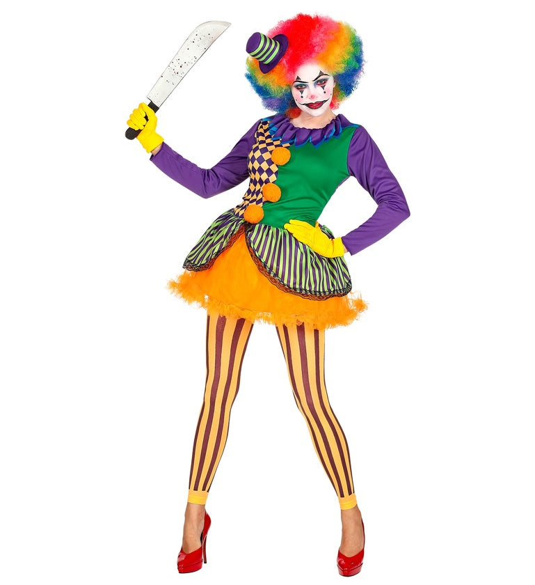 A woman in a colorful clown costume, holding a toy machete. The costume includes a purple, green, and checkered top, an orange tutu skirt, yellow and brown striped leggings, and a rainbow wig with a mini top hat.