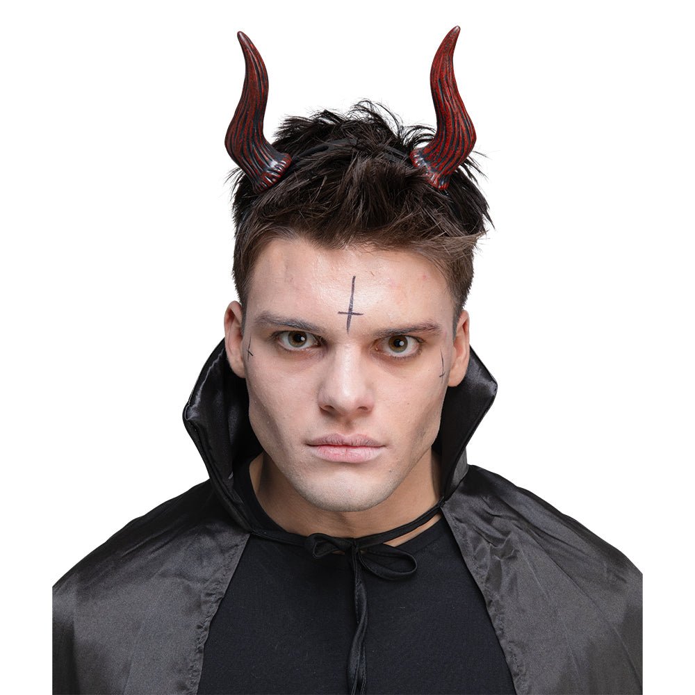 A man with dark makeup and a cape models a pair of adjustable, textured red and black satanic devil horns on a headband.