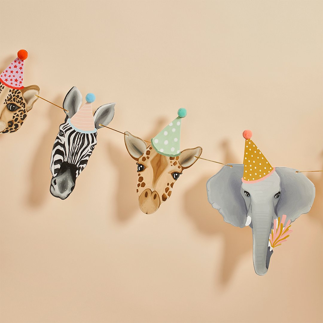 A close-up of safari animal heads bunting featuring a zebra, giraffe, and elephant wearing colorful 3D pom-pom party hats.