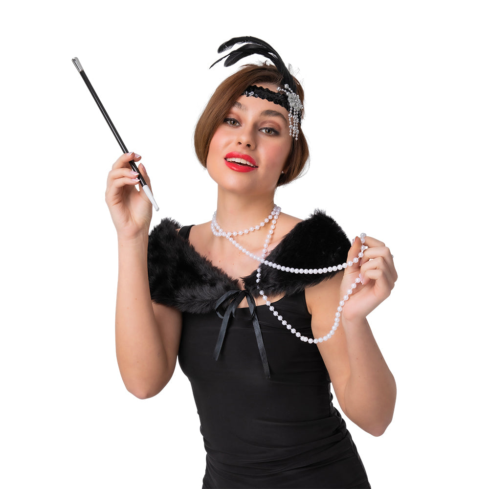 A close-up of a woman in a 1920s costume, playfully holding a string of faux pearls and a retro cigarette holder, styled with a black faux fur stole and feathered headband.