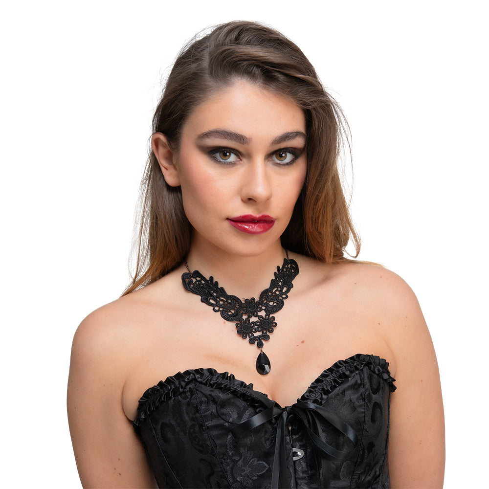 A woman wearing a black corset looks to the side while modeling an intricate black lace gothic choker with a dangling black gem.