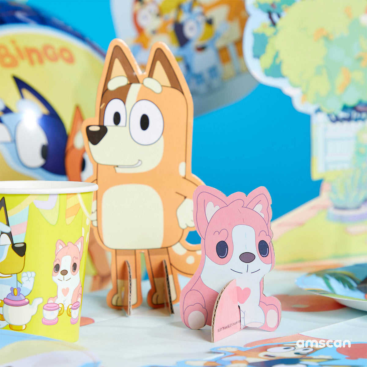 Close-up of Bluey party table decorations featuring standing cardboard cut-outs of Mum Chilli and the pink toy Floppy on a decorated party table.