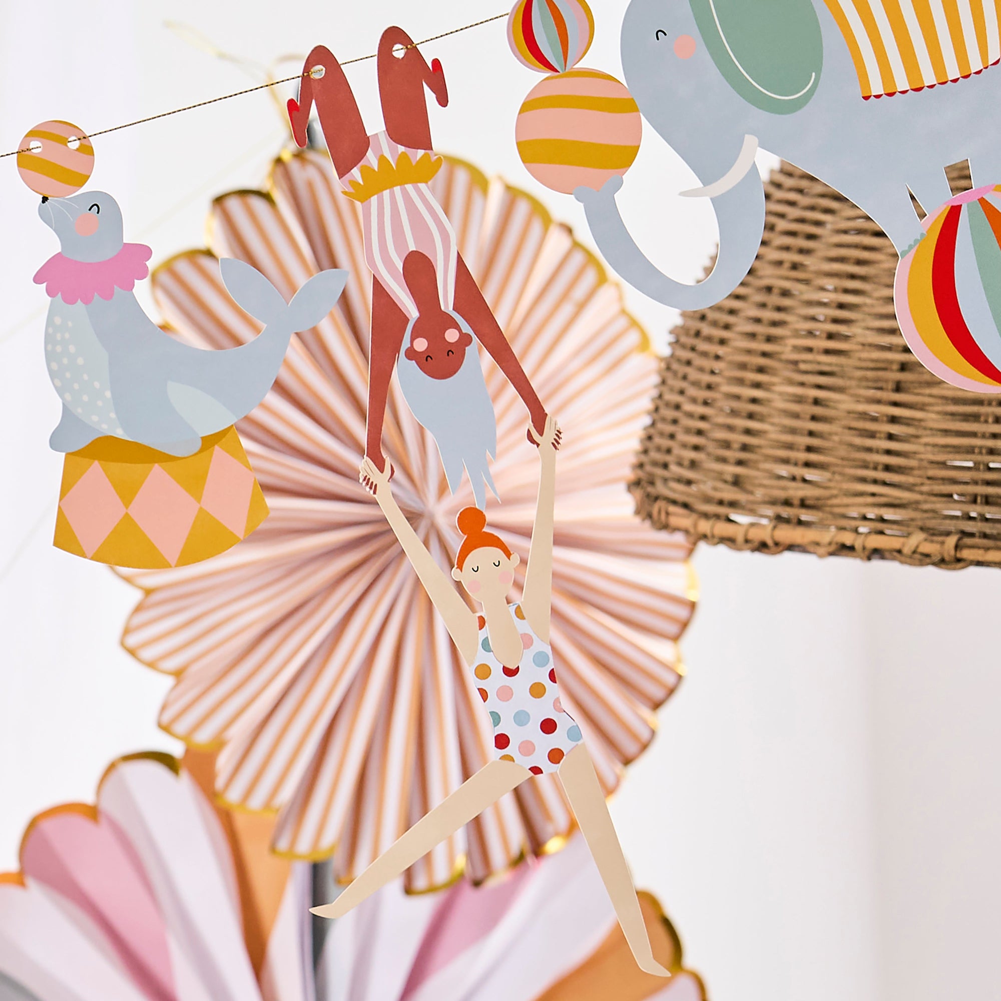 Close-up of a circus garland featuring a seal balancing a ball, an elephant, and two acrobats in a mid-air performance.