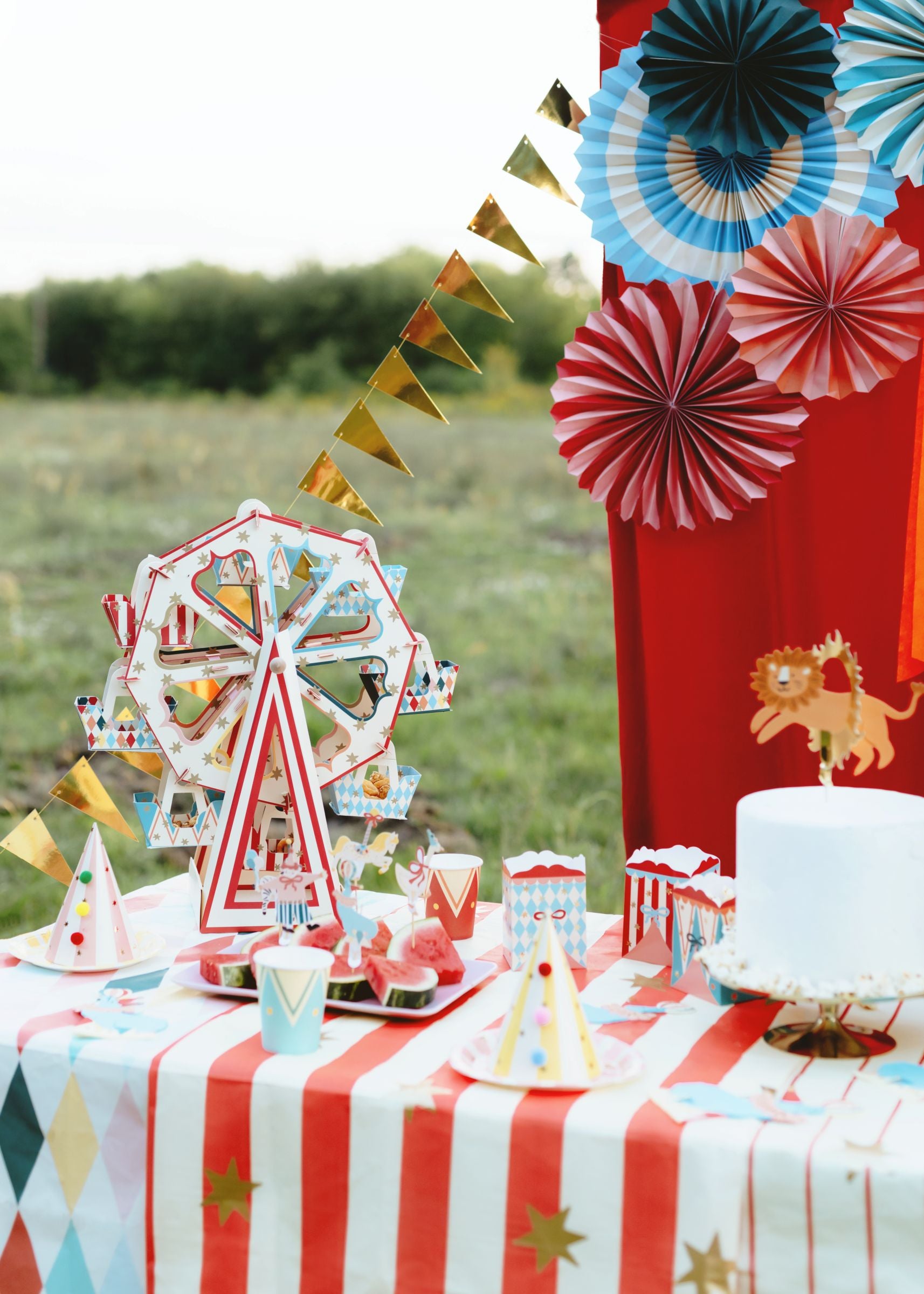 Outdoor circus-themed birthday party with decorative rosettes, balloons, and a festive snack table.