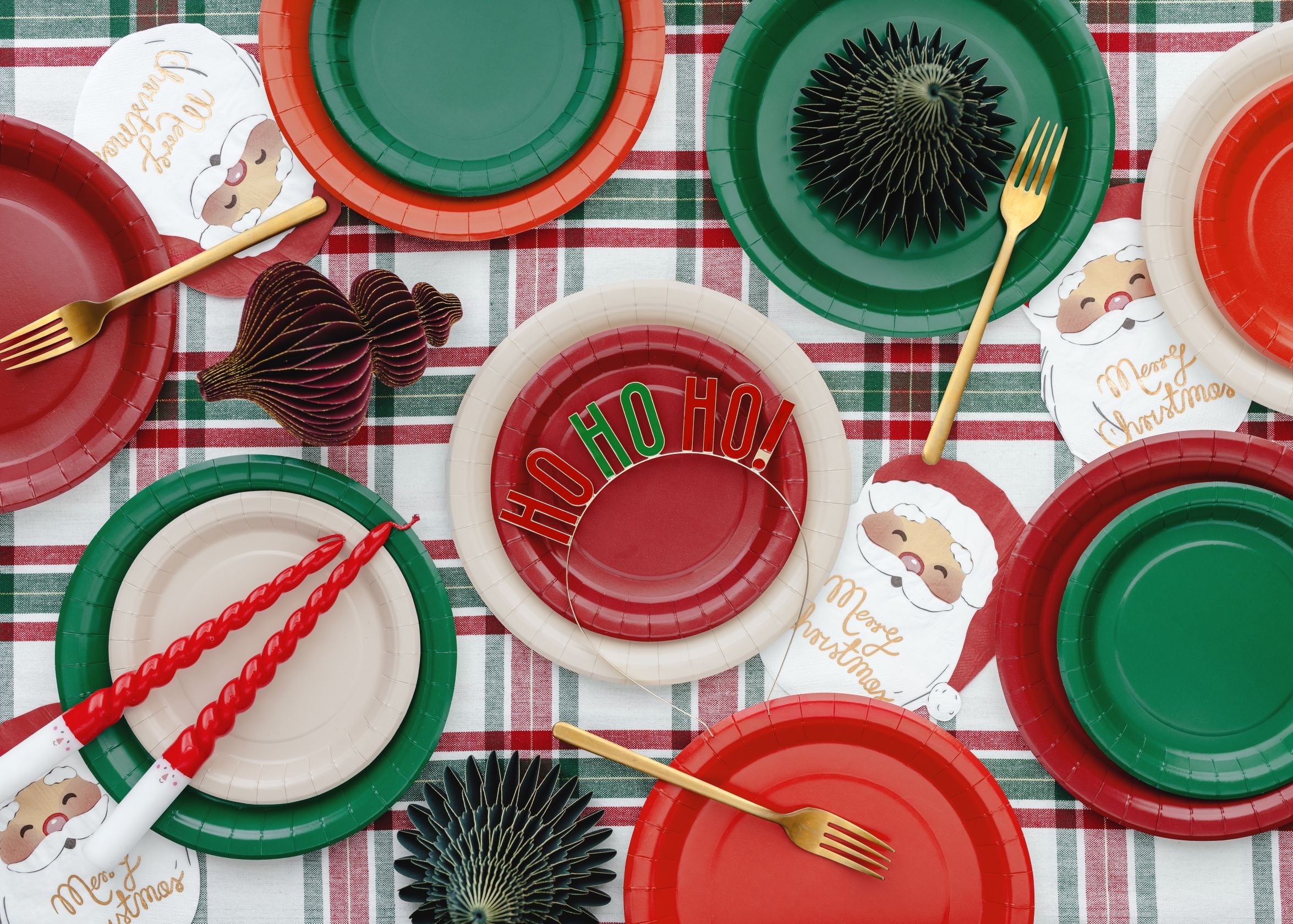 A festive Christmas table setting using red, white, and dark green paper plates and tableware.