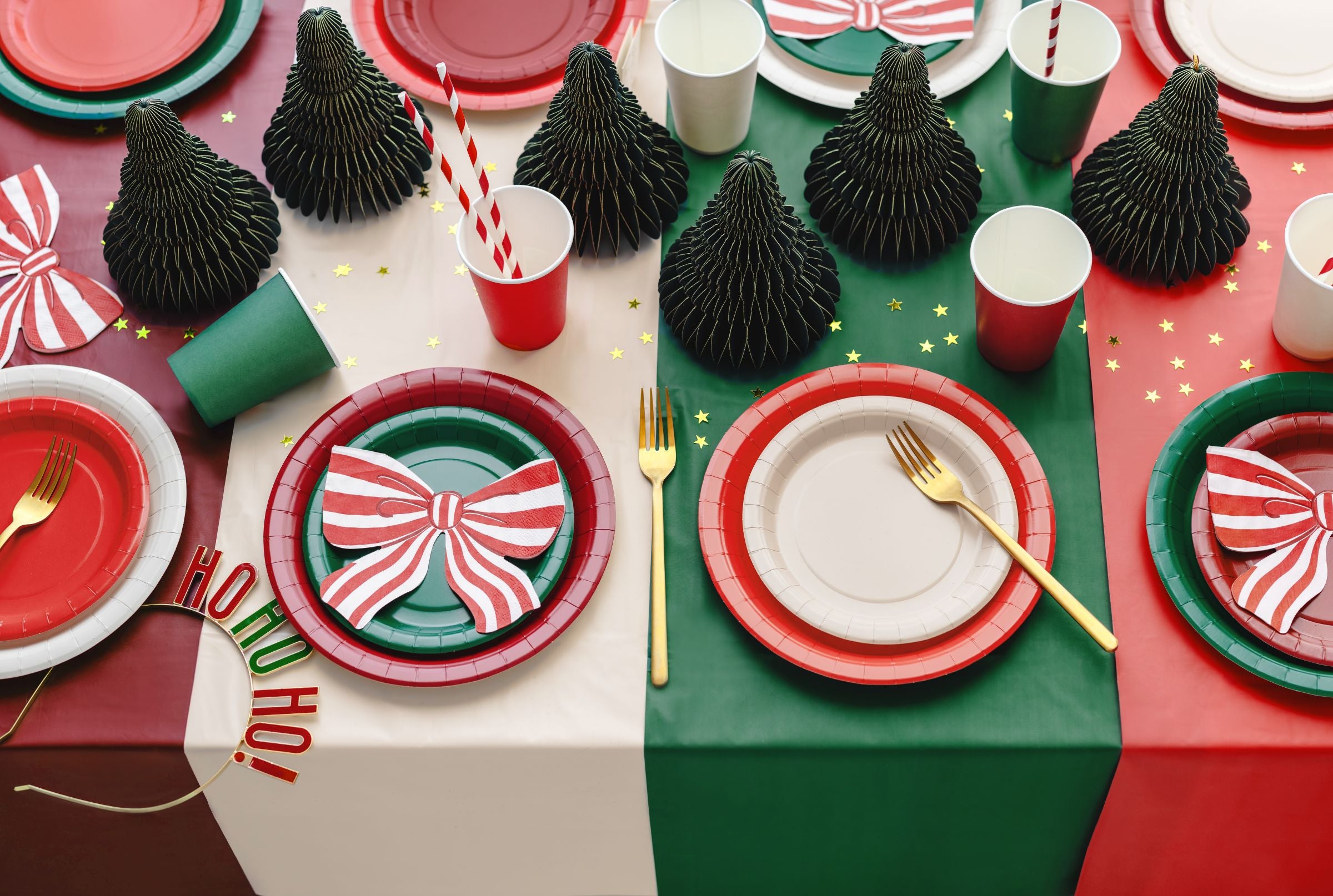 A festive Christmas table setting using the dark green and red tablecloths as a split-color base, adorned with party tableware.