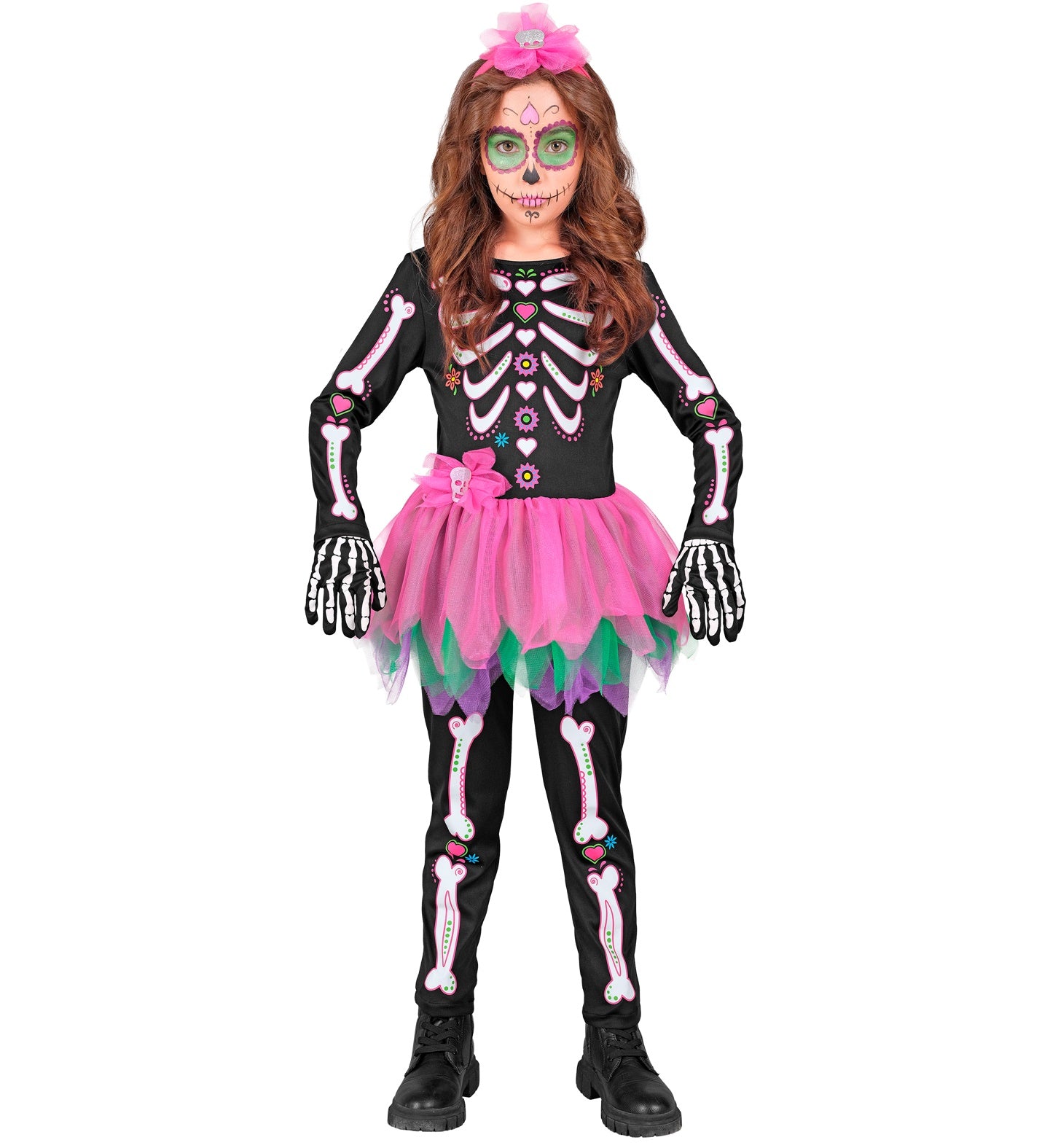 A child in a Day of the Dead skeleton costume, standing with hands on their hips. The costume is a black jumpsuit with colorful skeleton bones and flowers, a pink and green tutu skirt, and a pink floral headband.