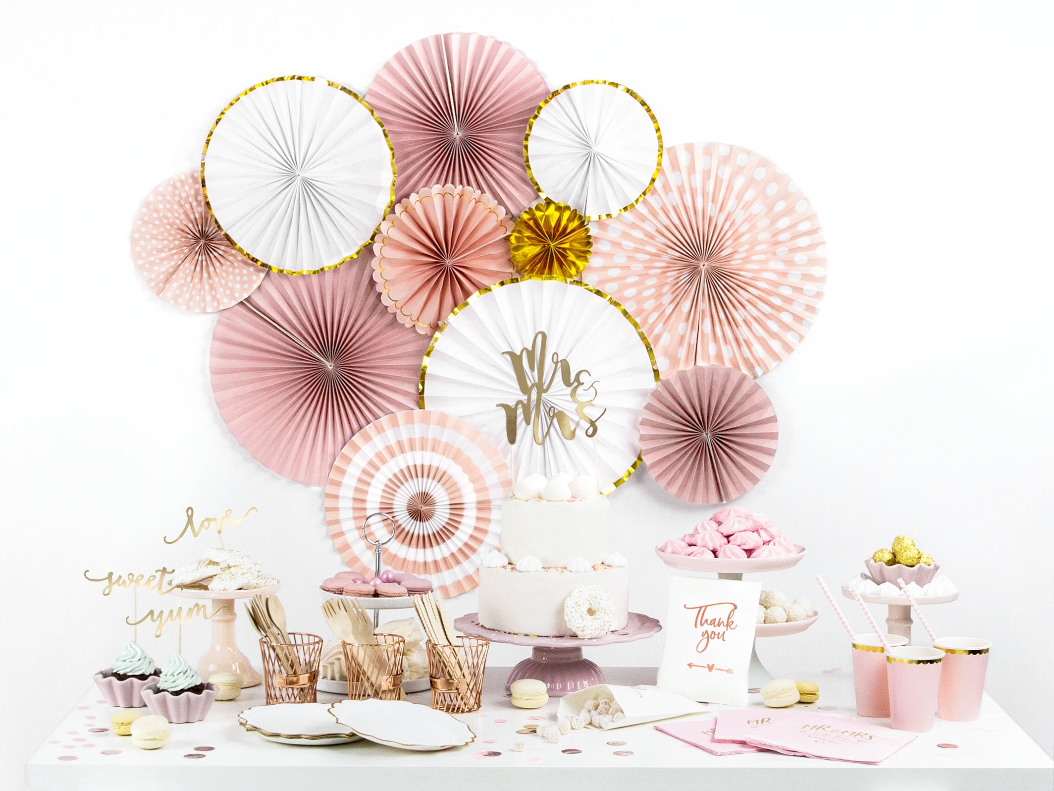 Elegant white and gold paper fans used as a wall backdrop for a sophisticated wedding dessert table.