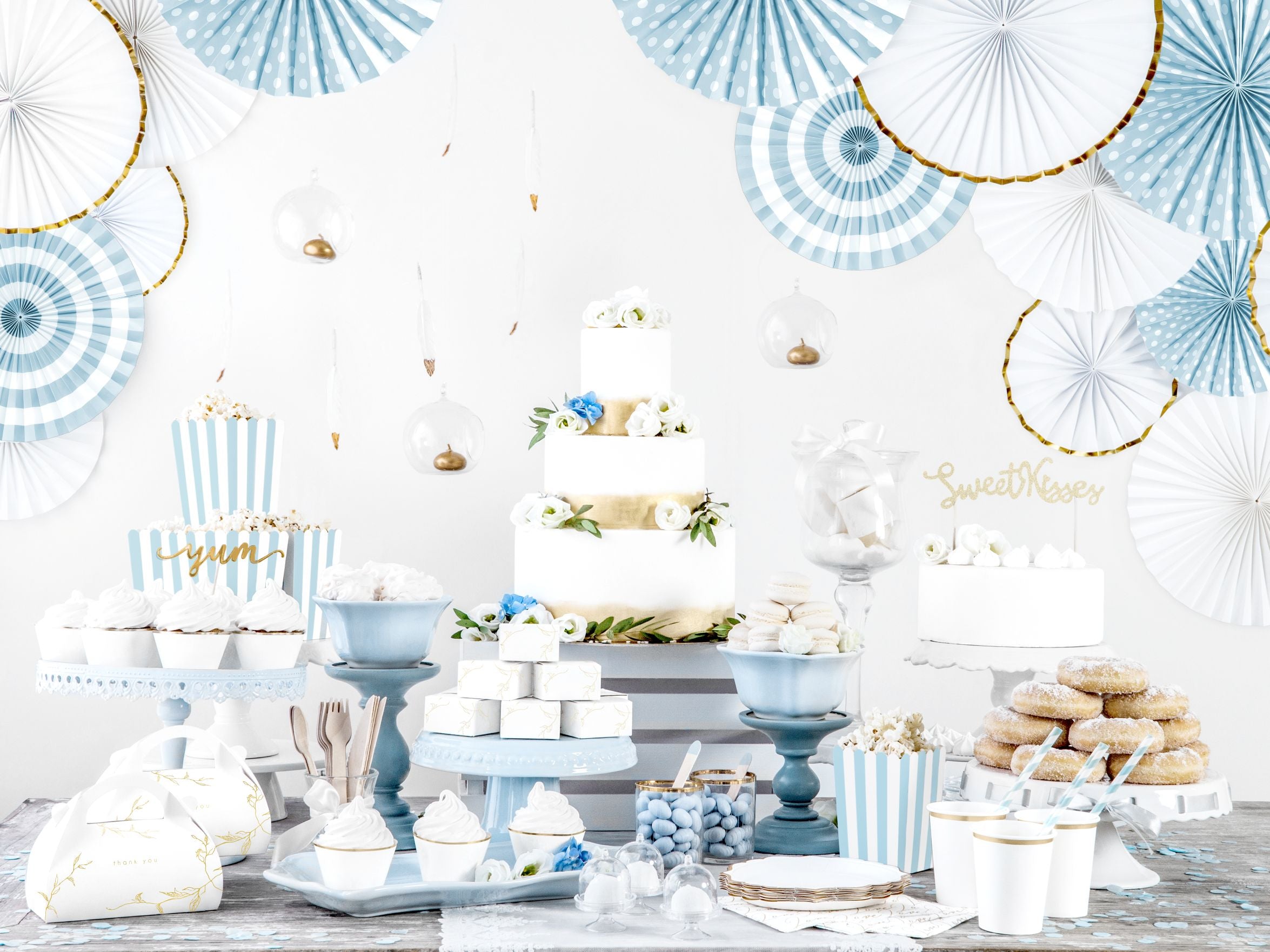 Blue and white fan rosettes with gold trim used to decorate a tiered cake display for a celebration.