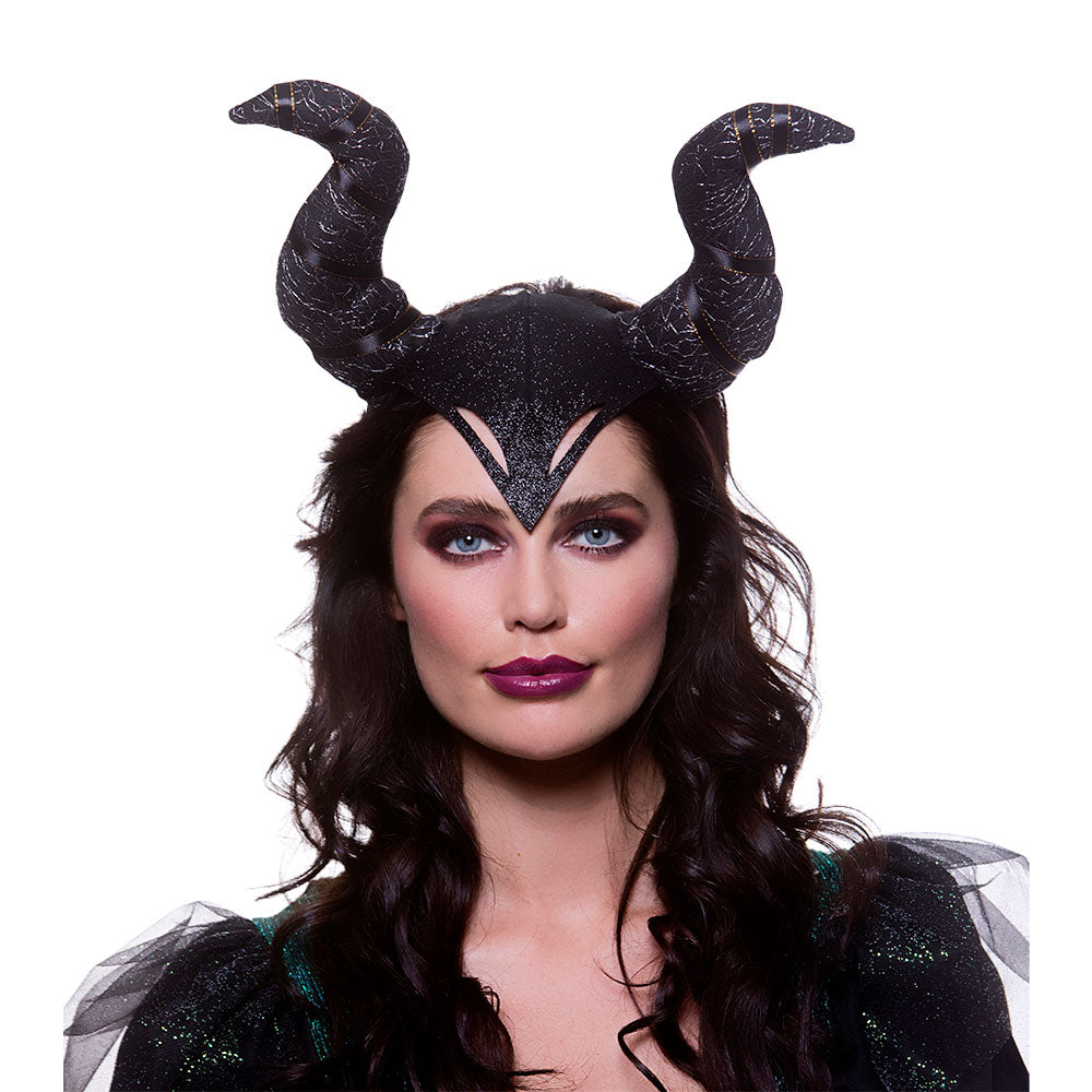 A person wearing a black, curved horns headpiece in the style of Maleficent, posing with dramatic makeup and dark hair, against a white background.