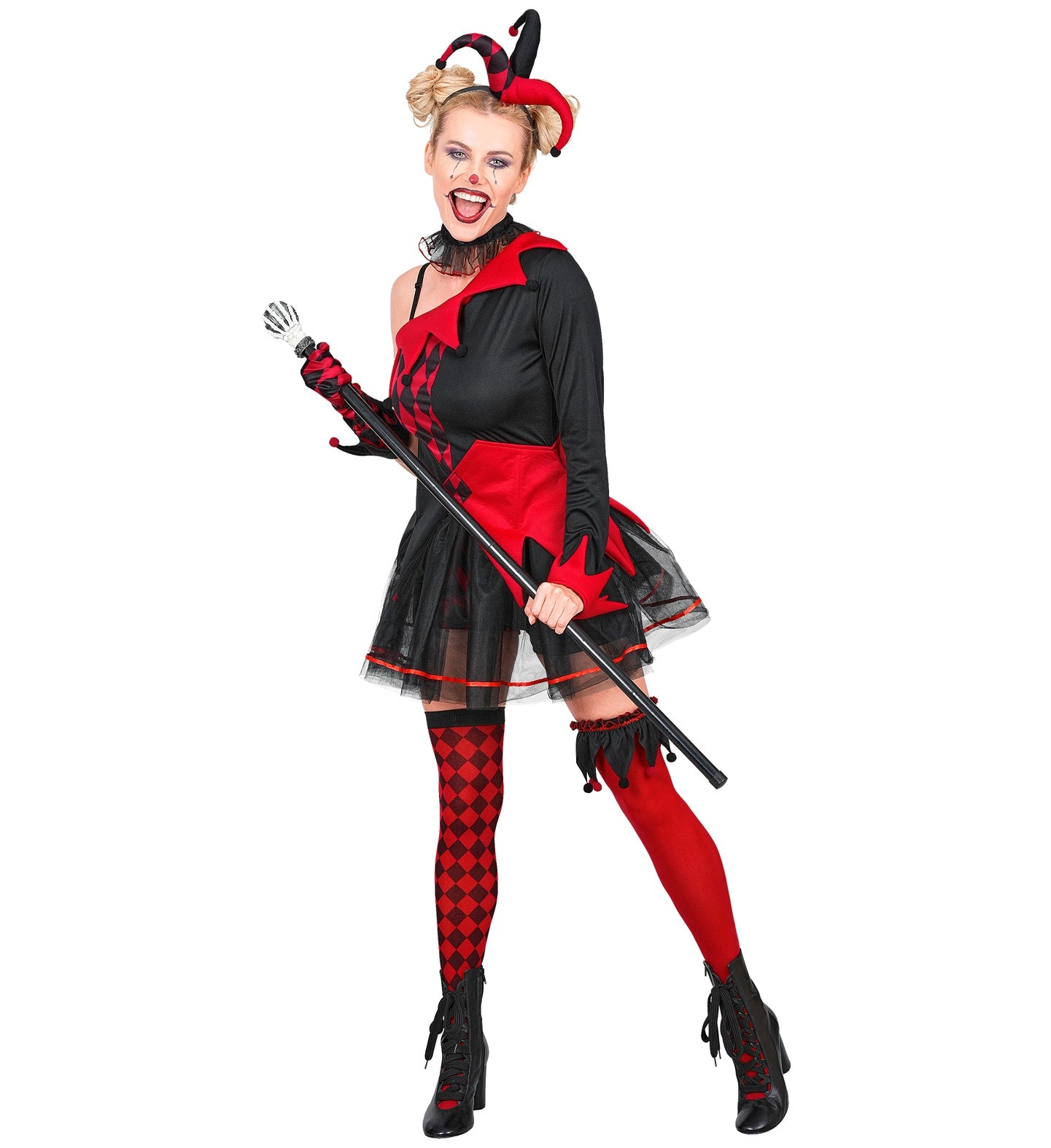 A full-length front view of a woman posing playfully in a red and black evil jester lady costume, showcasing the sweetheart neckline dress, black shorts, mismatched thigh highs, a ruffled neck choker, and a jester hat headpiece.
