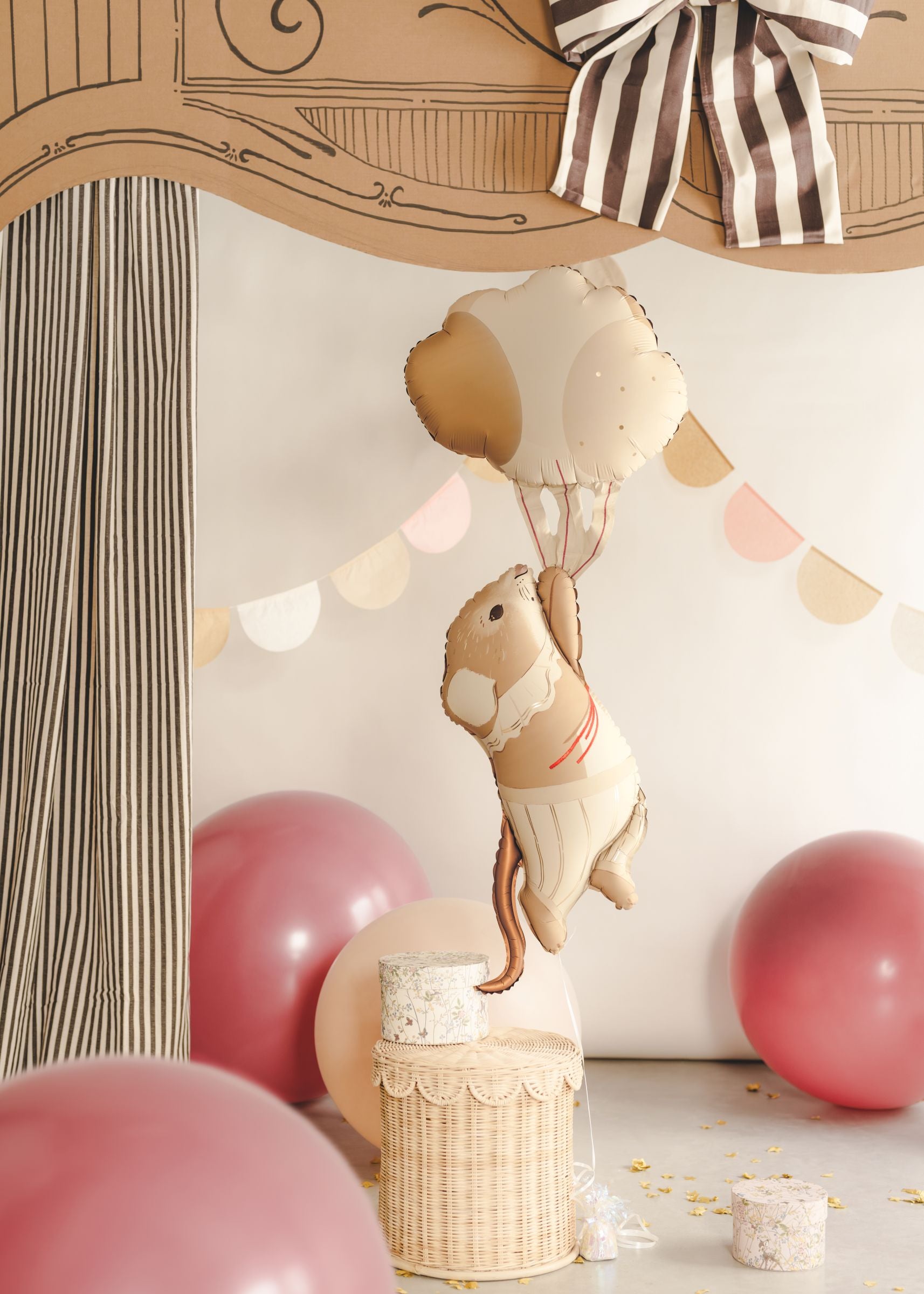 A close-up of a giant foil balloon shaped like a vintage mouse wearing a frilly collar, floating away while holding a bunch of cream and beige balloons.