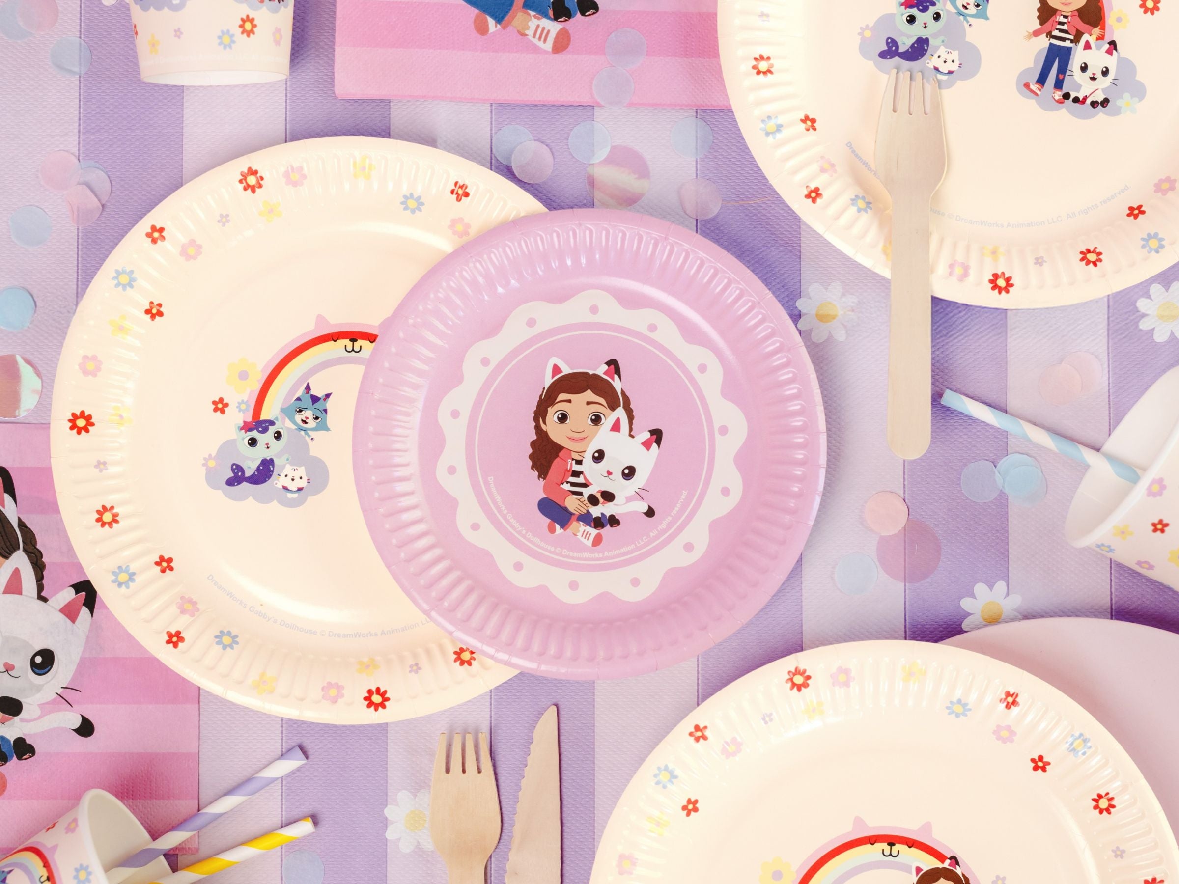 Gabby's Dollhouse themed birthday party table with matching plates, cups, napkins, and a purple striped tablecloth.