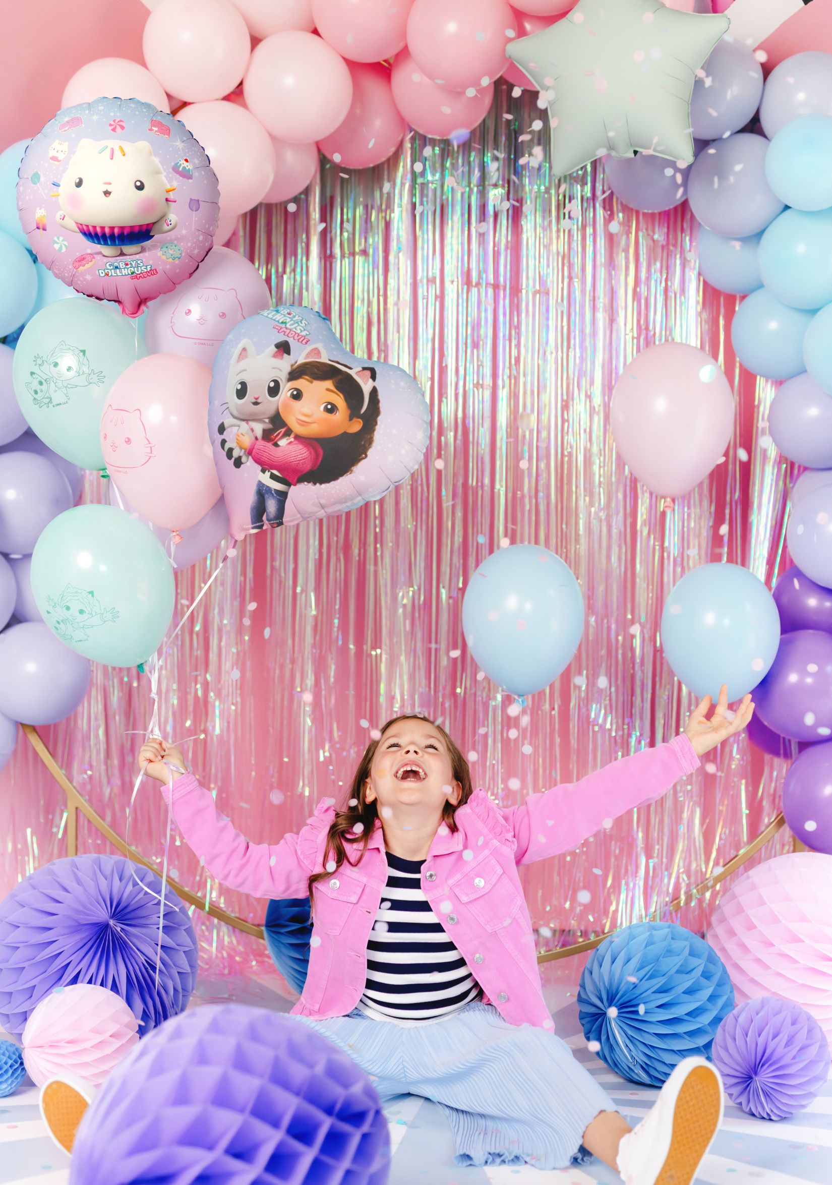 A young girl celebrating with a Cakey Disc Foil Balloon amidst pink and purple party decorations.
