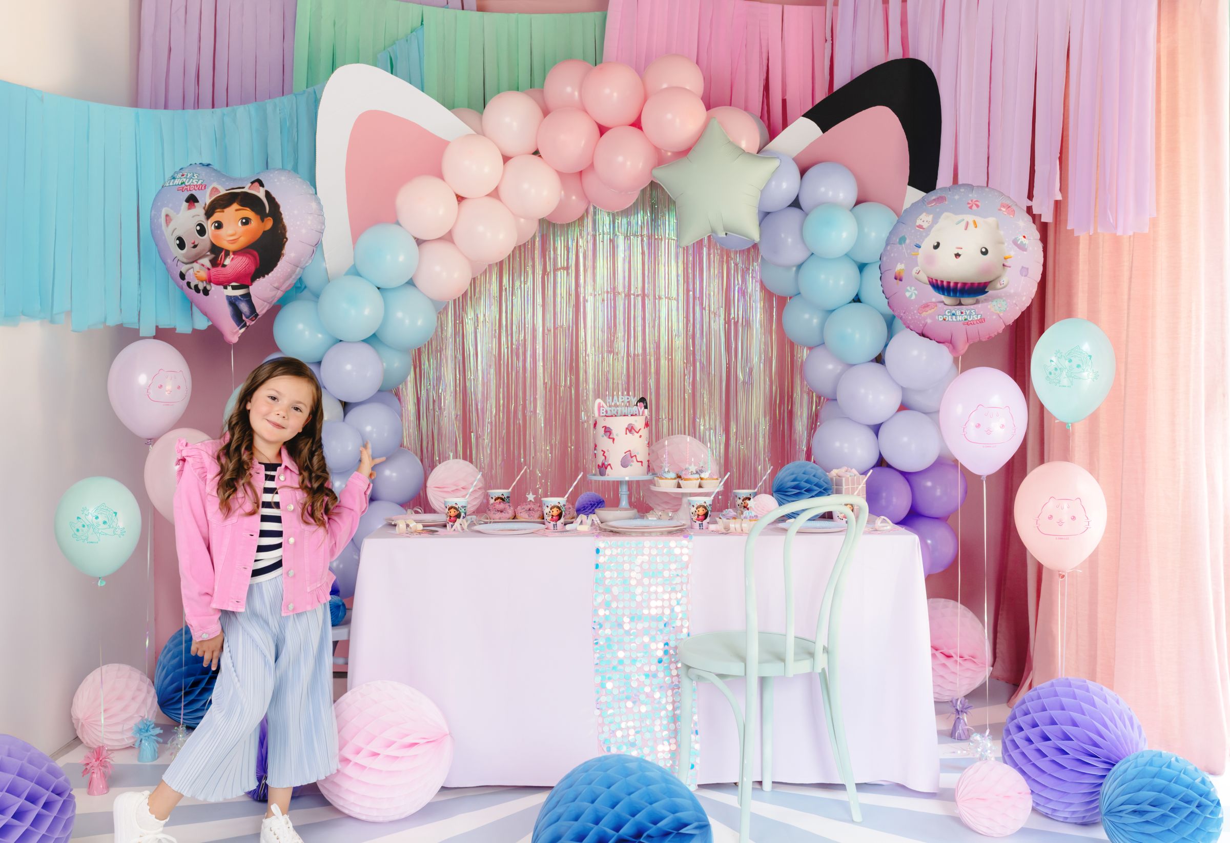 A Cakey Cat disc balloon floating above a decorated party table with Gabby's Dollhouse themed plates.