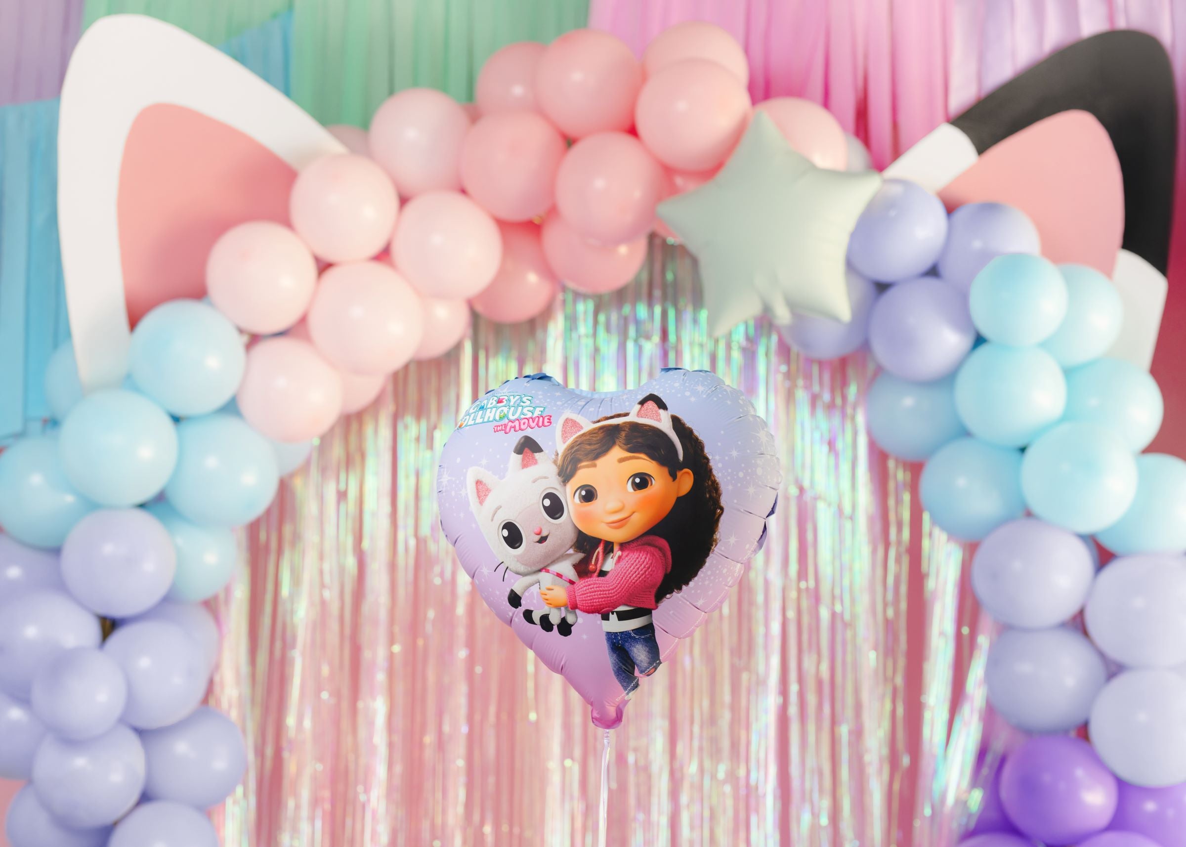 Colorful balloon arch with a heart-shaped Heart-shaped foil balloon featuring Gabby and Pandy Paws from Gabby's Dollhouse at a party.