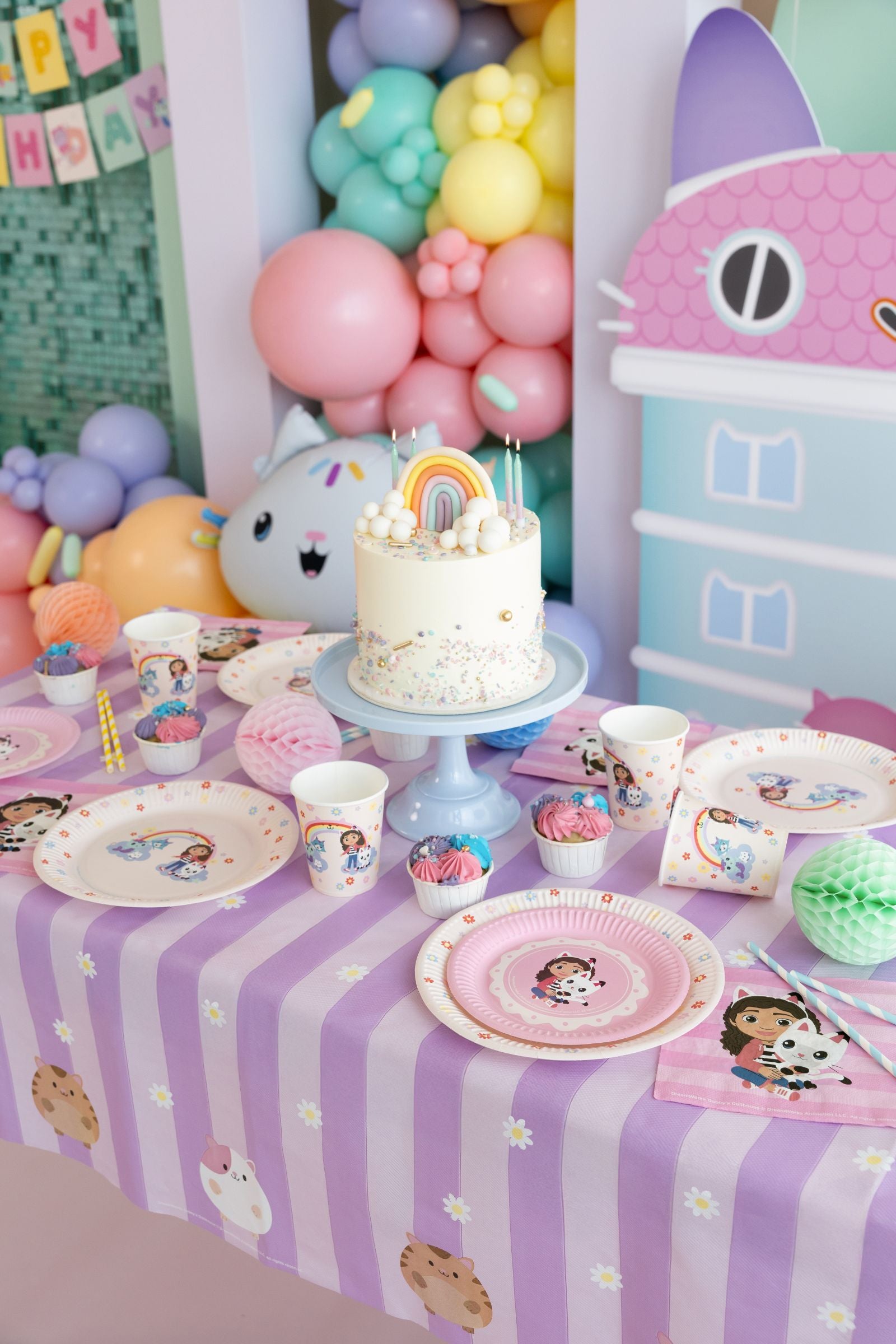 A beautifully decorated Gabby's Dollhouse party table featuring 23cm movie plates and character balloons.