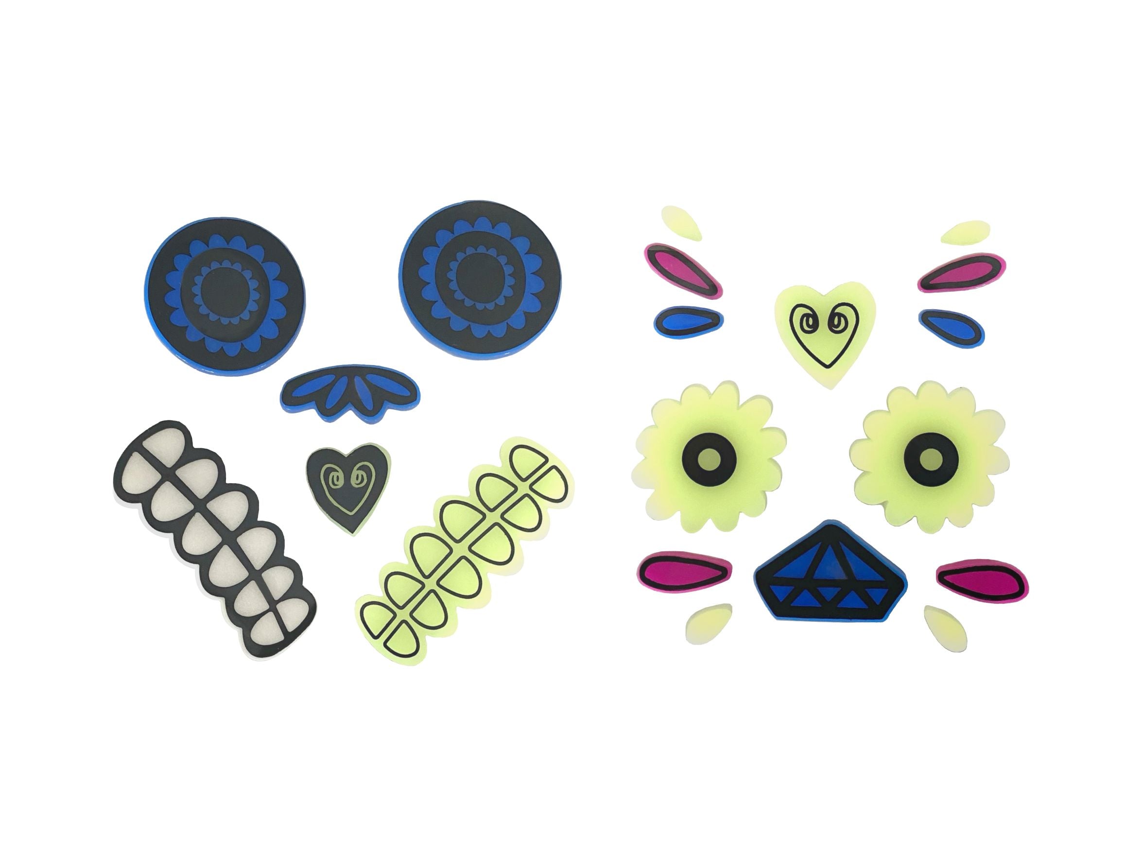 Two sets of glow-in-the-dark gel stickers designed for Day of the Dead themed pumpkin faces. One set features black and blue patterns with bone-like mouth pieces, and the other has yellow flowers, pink accents, and a blue diamond nose, all isolated on a white background.