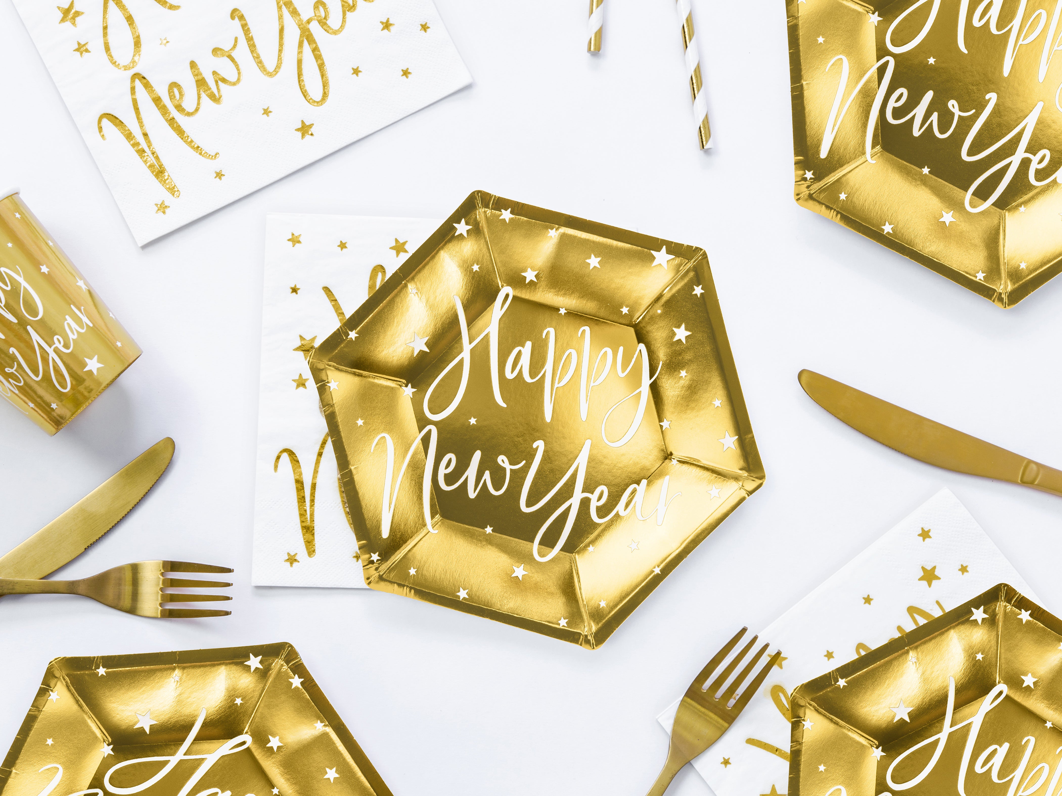 New Year's Eve tablescape with gold hexagonal plates, white napkins, and gold cutlery.